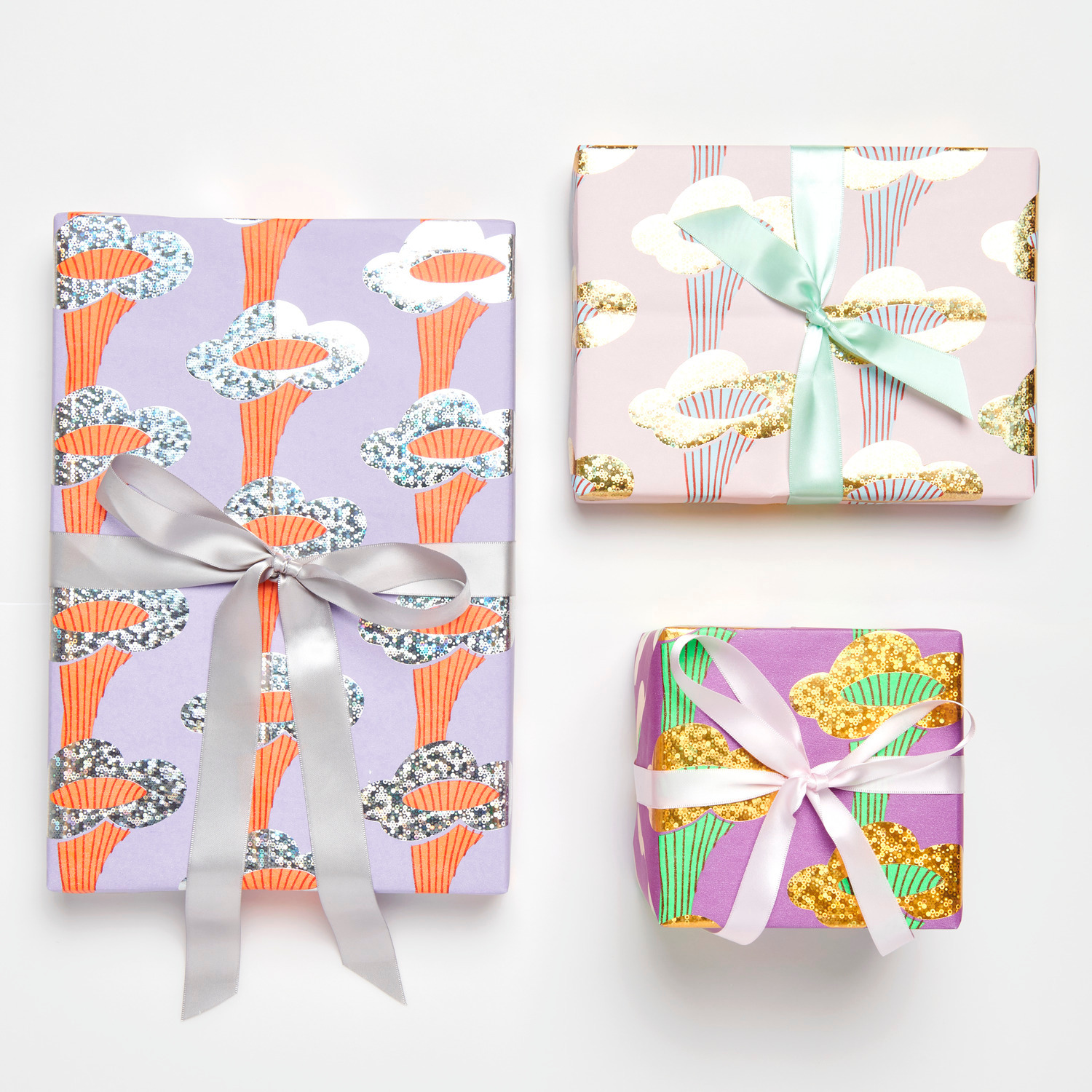 Geschenkpapier Pfifferlinge Flieder: Drei Geschenke in buntem Papier mit Pilzmotiven, verziert mit Schleifen.