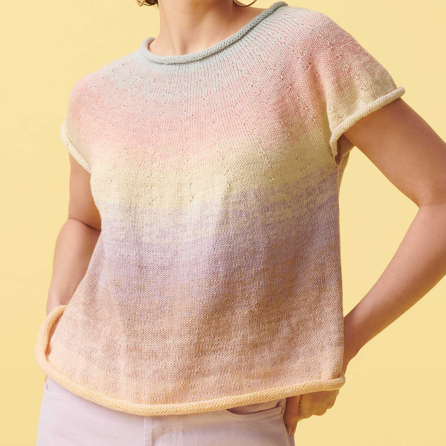 Strickanleitung Top aus Creative Cotton Dégradé Lucky 8: Pastellfarbenes, kurzärmeliges Stricktop mit sanften Farbverläufen auf gelbem Hintergrund.