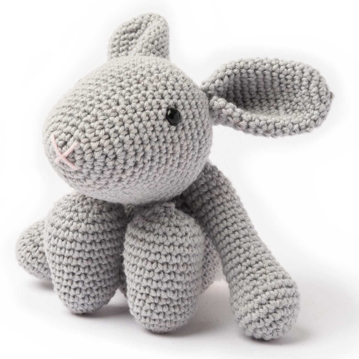 Häkelset Ricorumi Puppies Hase: Ein grauer, gehäkelter Hase von Rico Design mit langen Ohren und schwarzen Augen.