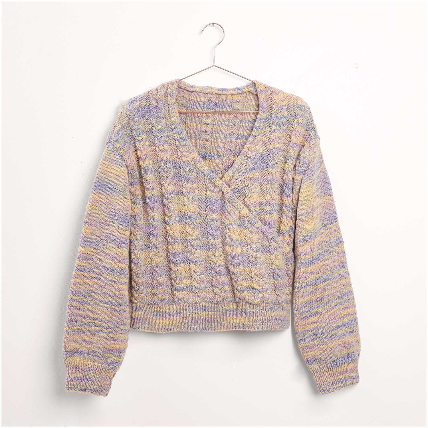 Strickset Pullover Modell 07: Ein gestrickter Pullover in Pastelltönen, hängend an einem Kleiderbügel.