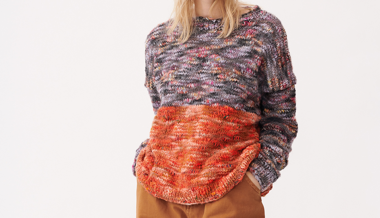 Strickanleitung Pullover aus Creative Wooly Waves: Bunter Pullover mit grauem und orangefarbenem Muster, getragen von einer Frau.