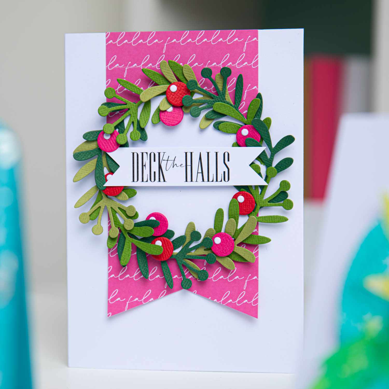 Thinlits Die Set Buds & Branches: Festliche Karte mit grünem Kranz und roten Beeren auf rosa Hintergrund.