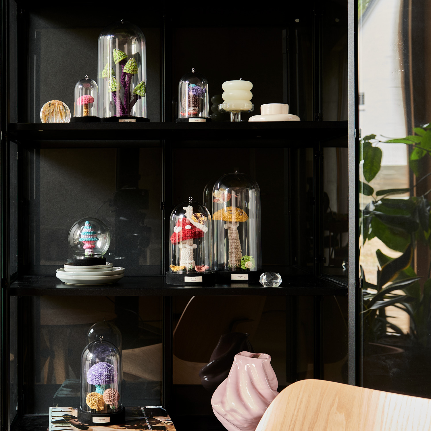 Creative Ricorumi dk: Dekorative Glasglocken mit bunten Garnen und kreativen Figuren auf einem Regal. Ideal für stilvolle Wohnräume.