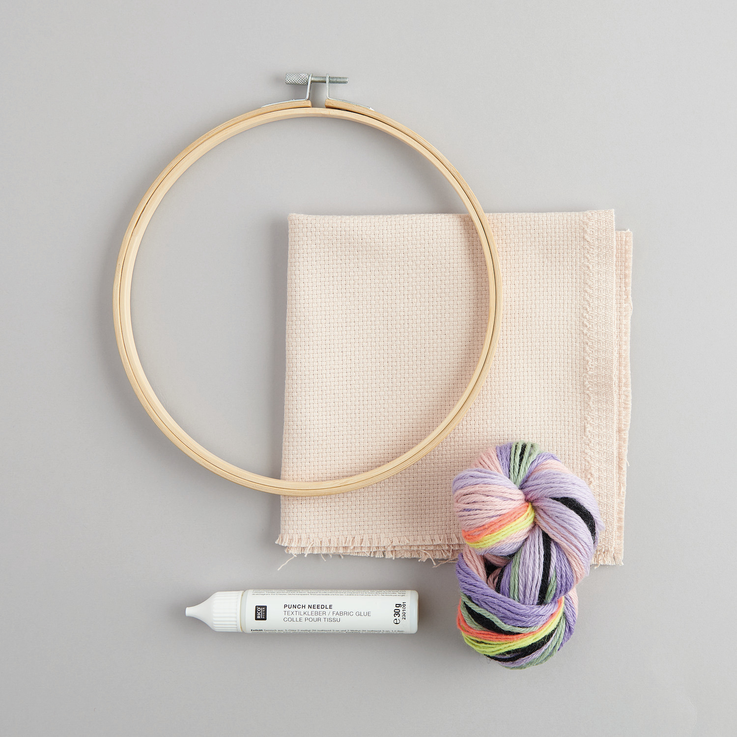 Punch Needle Packung Schmetterling: Ein Stickrahmen, bunte Wolle und Stoff von Rico Design auf grauem Hintergrund.
