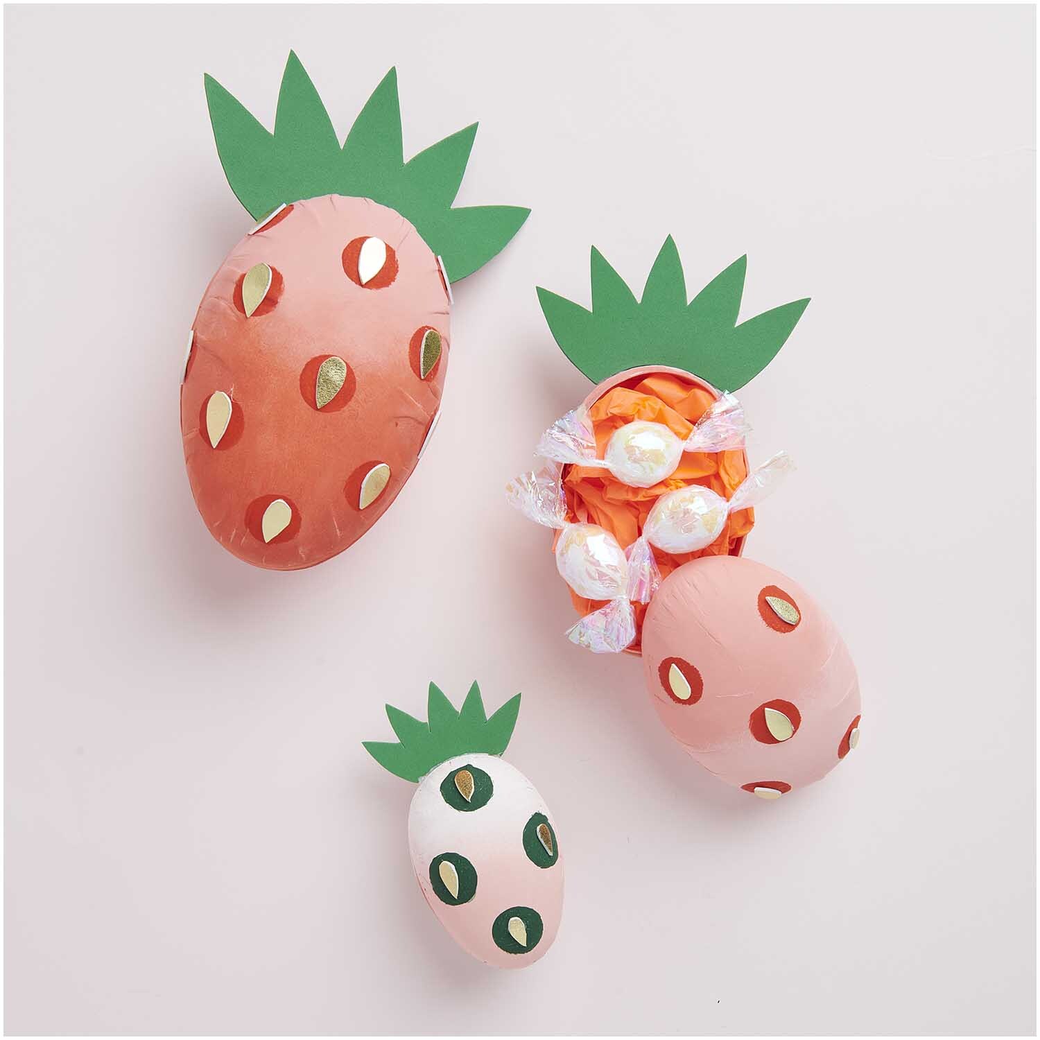 Pappmaché Eier in Form von Erdbeeren mit grünem Blattmuster, ideal für kreative Dekorationen.