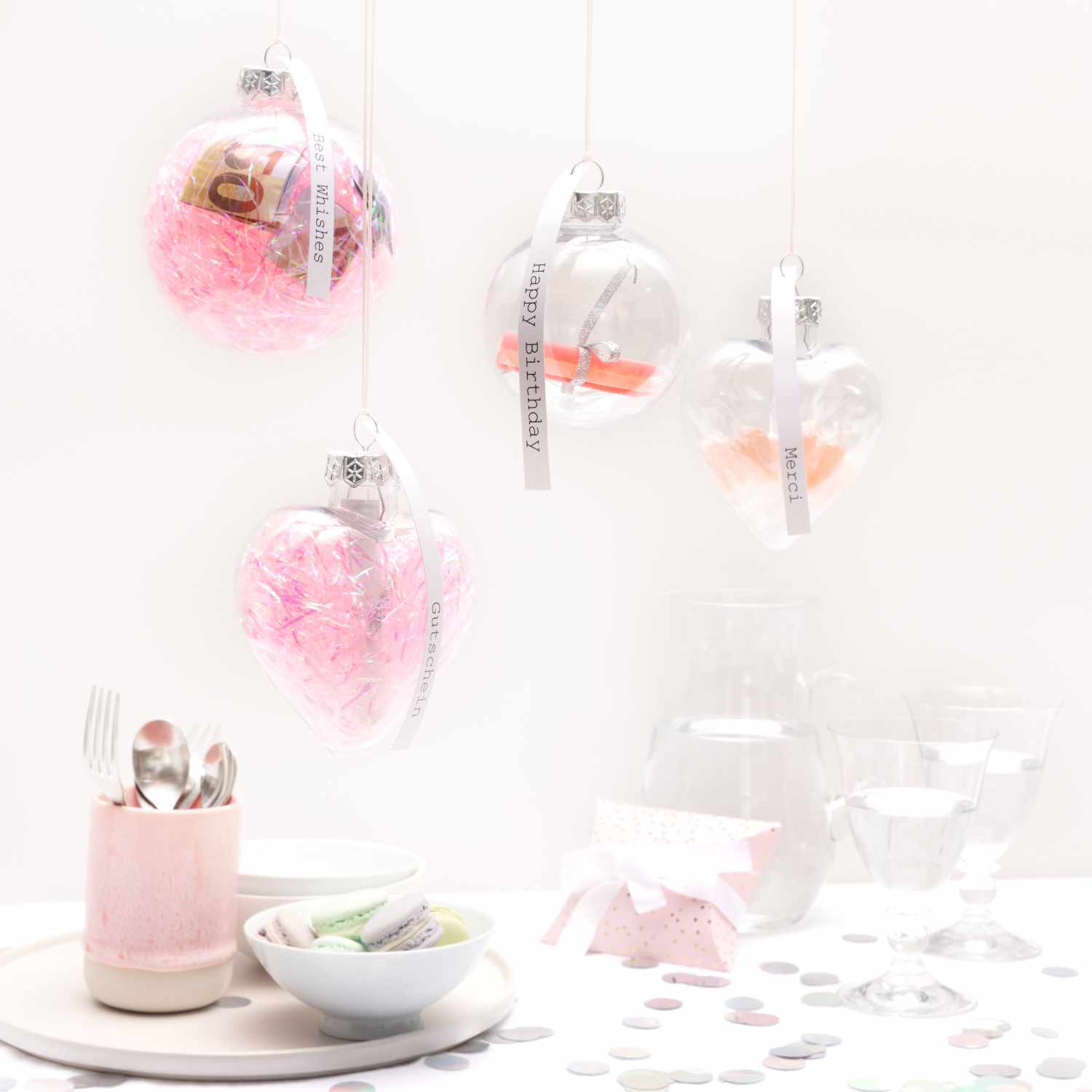 Weihnachtskugel Herz aus Kunststoff, dekoriert mit rosa Füllung, hängt neben anderen transparenten Kugeln.