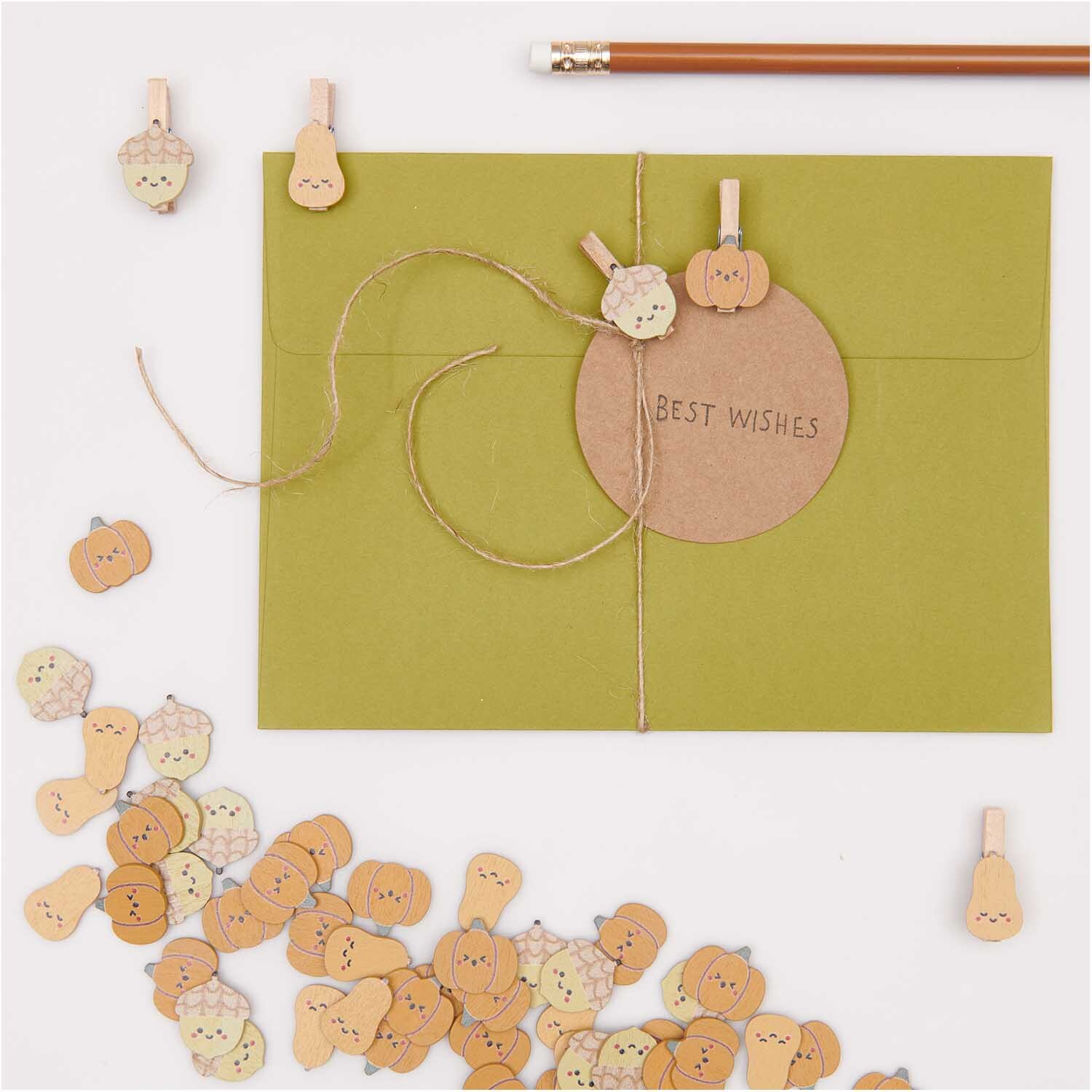 Holzclips Kürbis Mix: Bunte Kürbis-Clips von Rico Design auf grünem Umschlag mit "Best Wishes".