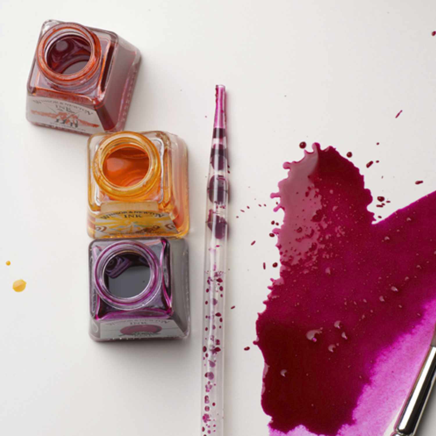 Zeichentusche 14ml von Winsor & Newton, drei Tintenflaschen in verschiedenen Farben neben einem Pinsel auf weißem Hintergrund.
