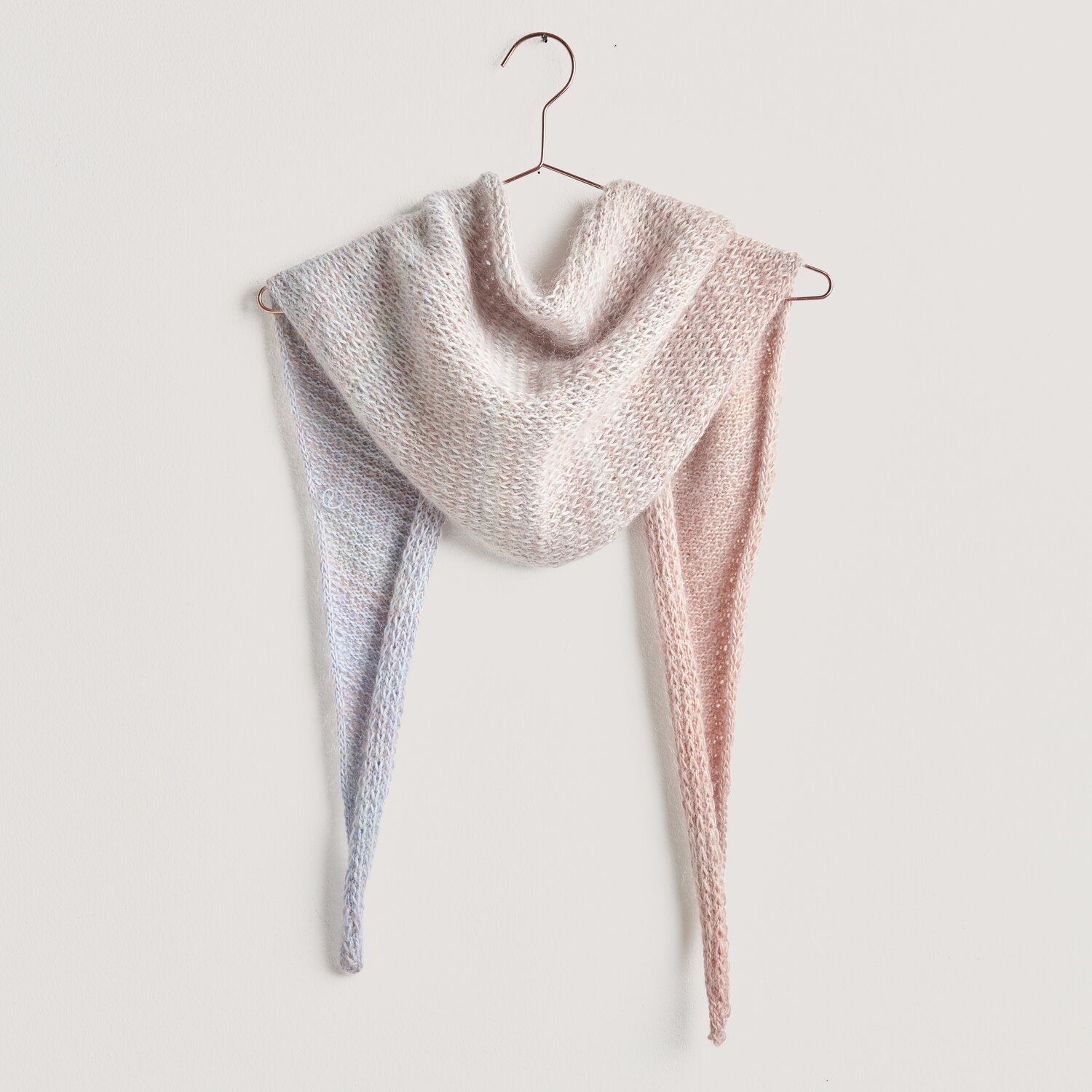 Strickset Dreieckstuch Modell 10b aus Lovewool No. 20, pastellfarbenes Tuch auf einem Kleiderbügel.