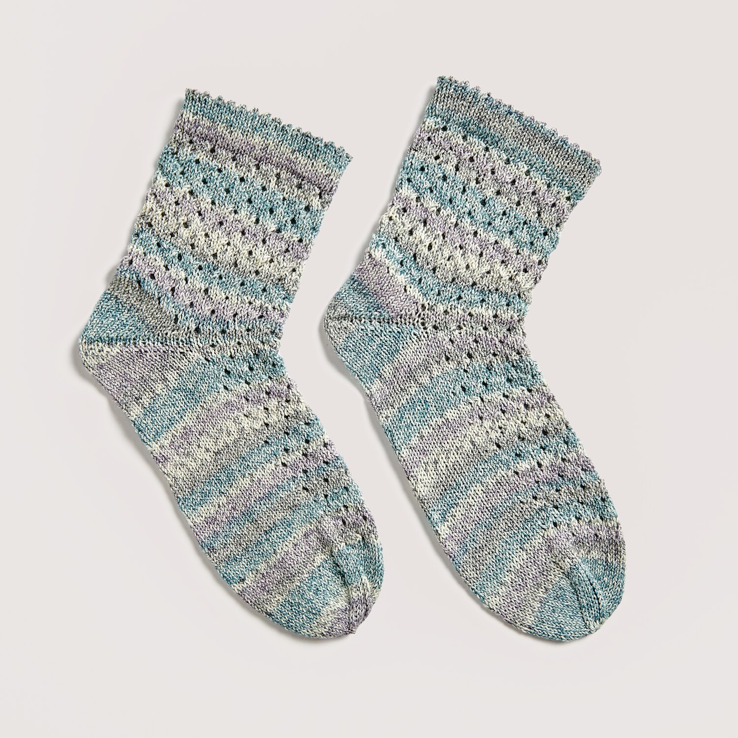 Strickset Socken Modell 14a aus Die Neue Masche No. 12, gestrickt in Aqua-Tönen, zeigt ein feines Lochmuster. Ideal für Frühling und Sommer.