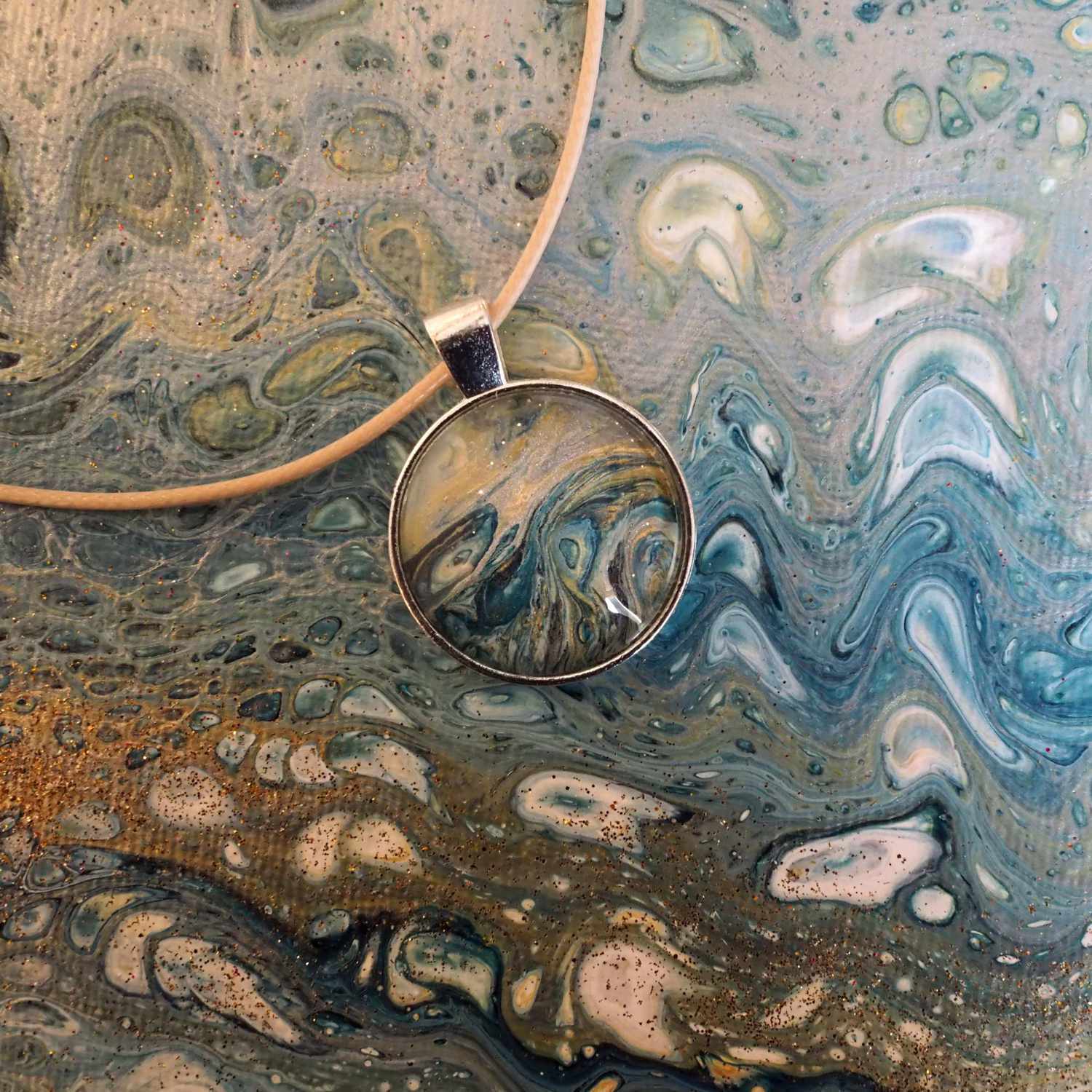 Anleitung DIY Pouring Schmuck: Anhänger mit abstraktem, blauem Muster auf passendem Hintergrund.