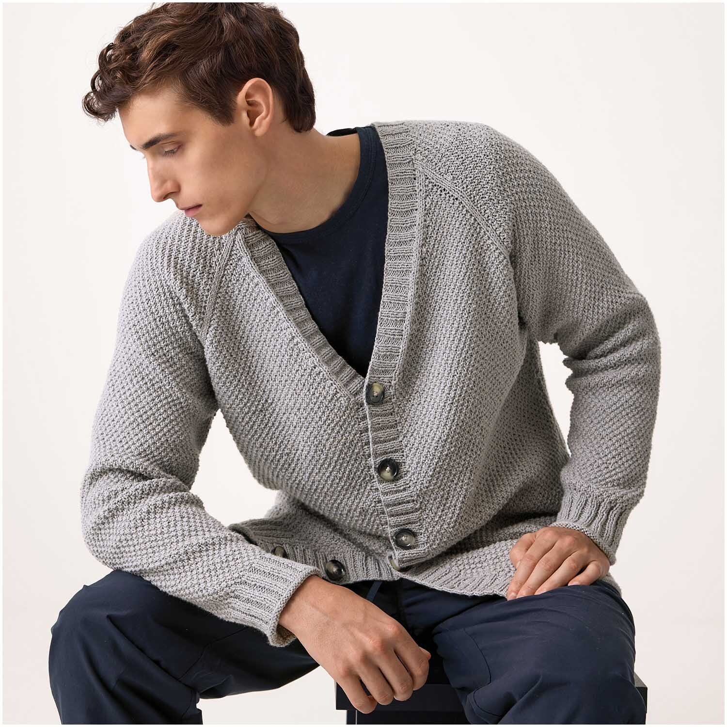 Luxury Organic Cotton Silk dk: Ein Mann trägt eine graue Strickjacke von Rico Design, sitzt entspannt und blickt zur Seite.