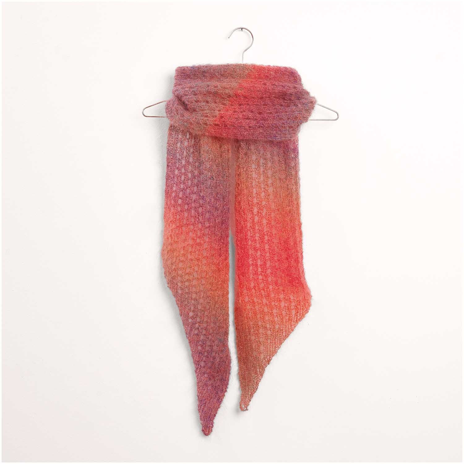 Strickset Tuch Modell 10: Ein handgestricktes Tuch in warmen Rottönen, elegant drapiert auf einem Kleiderbügel.