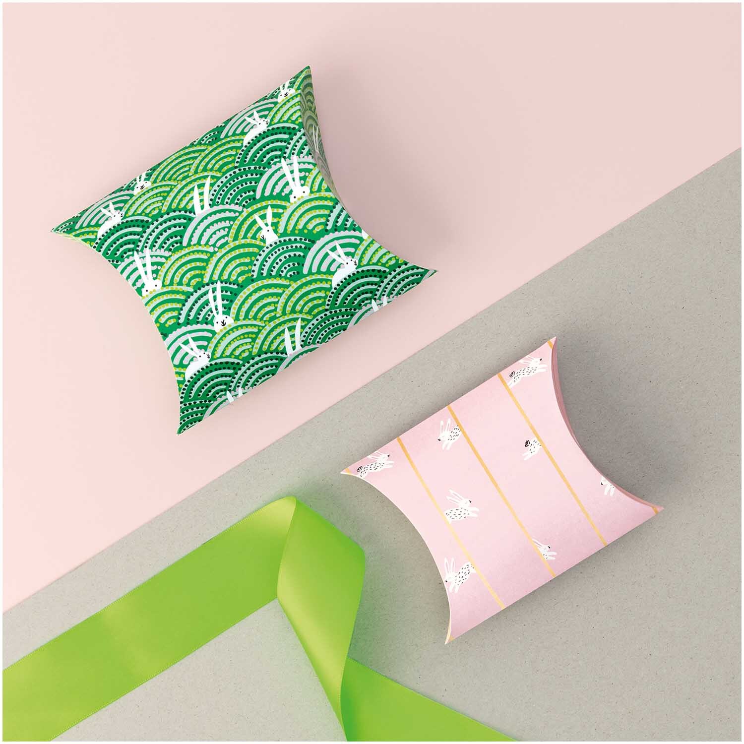 Paper Poetry Geschenkschachteln Bunny Hop 6 Stück, grün und rosa, dekorativ auf grauem Hintergrund mit grünem Band arrangiert.