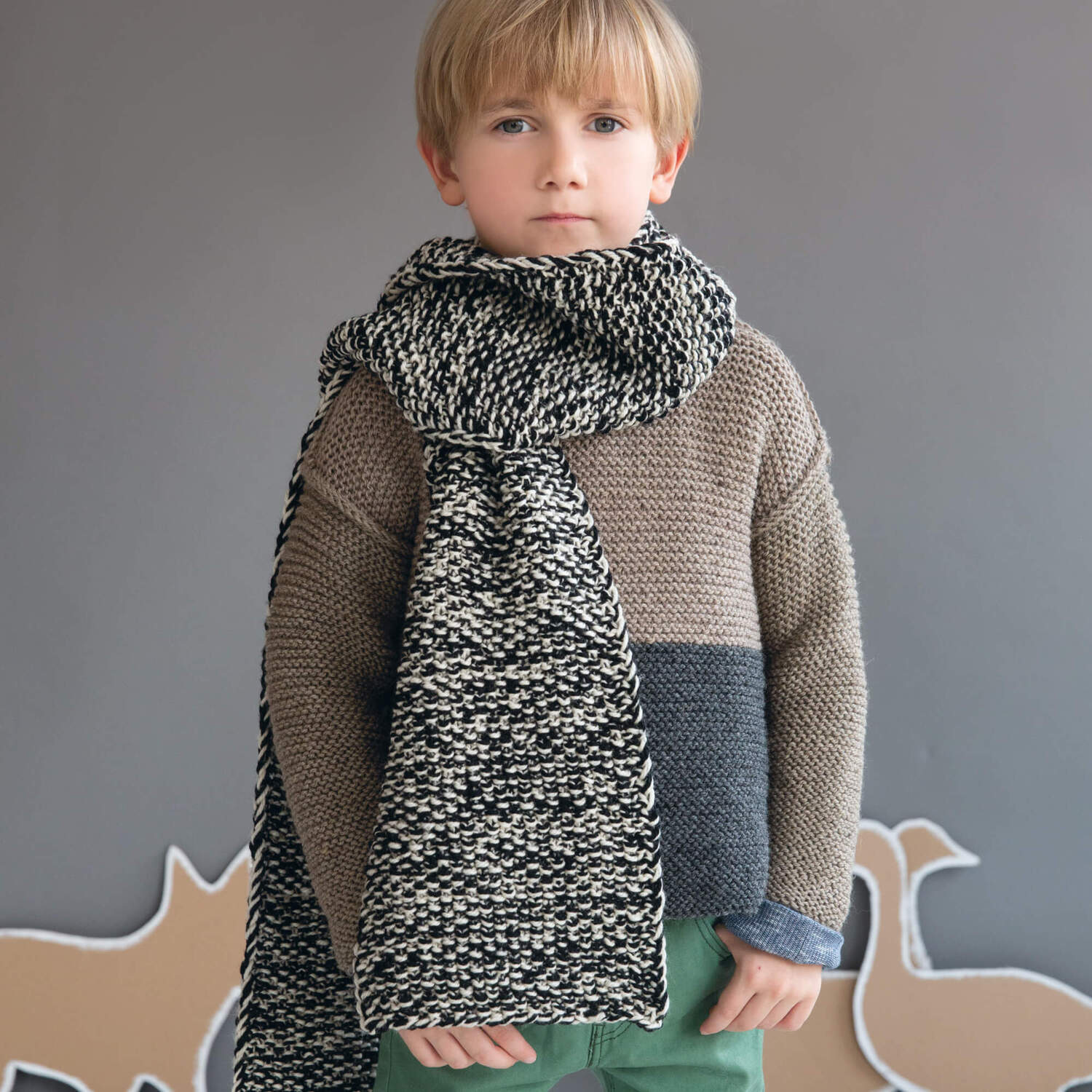 Strickanleitung Kinder-Perlmusterschal aus Soft Merino: Junge trägt einen gestrickten Schal in Schwarz-Weiß mit passendem Pullover.