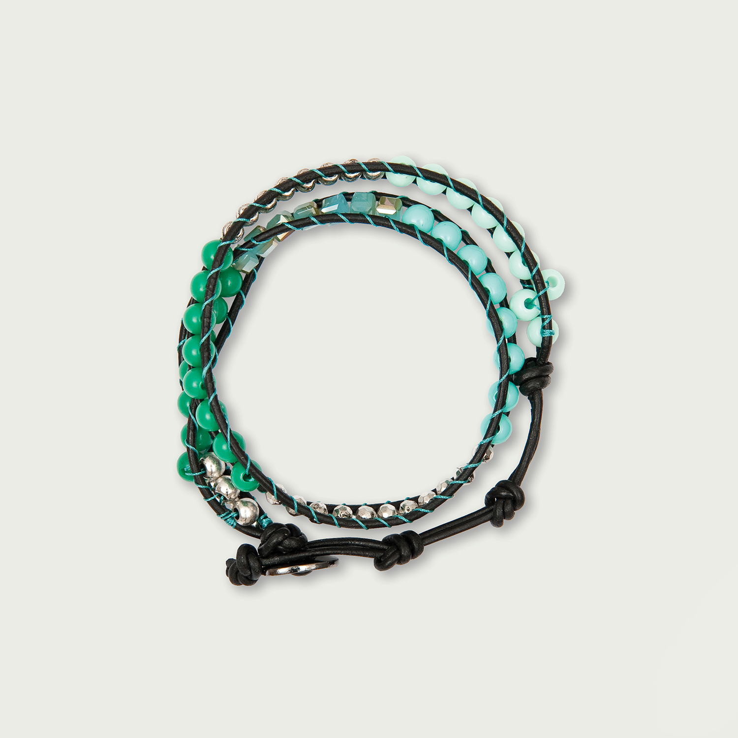 Anleitung Cooles Wickelarmband basteln: Geflochtenes Armband in Grün- und Blautönen mit schwarzen Akzenten.