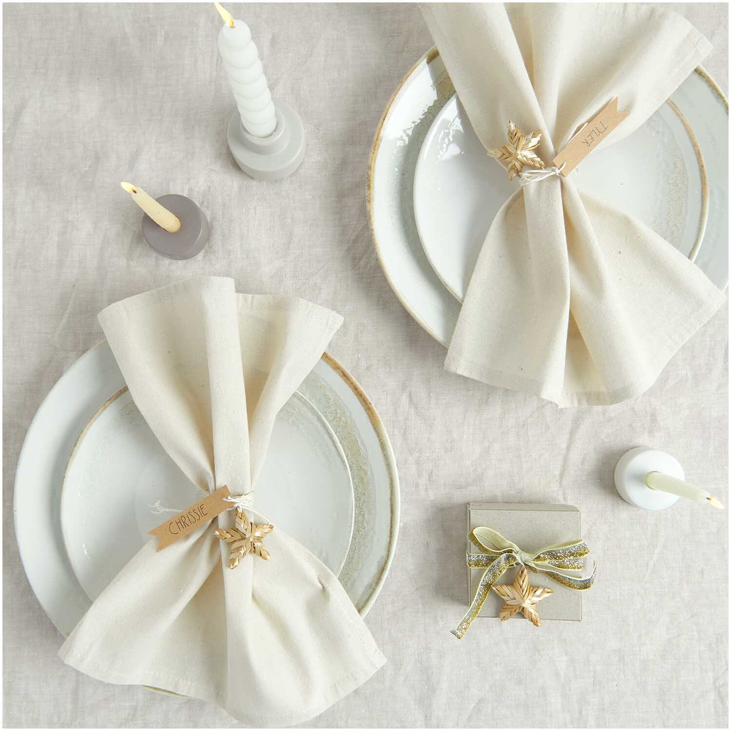 Stoffserviette 2 Stück natur von Rico Design auf elegant gedecktem Tisch mit Kerzen und Geschenkbox. Ideal für festliche Anlässe.