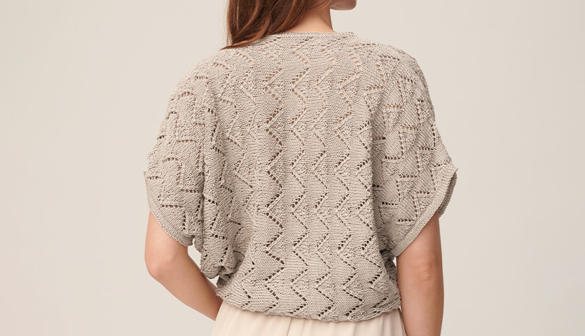 Strickanleitung Shirt aus Mille Fili: Rückansicht eines beigen, gestrickten Shirts mit Zickzackmuster. Ideal für stilvolle Sommeroutfits.