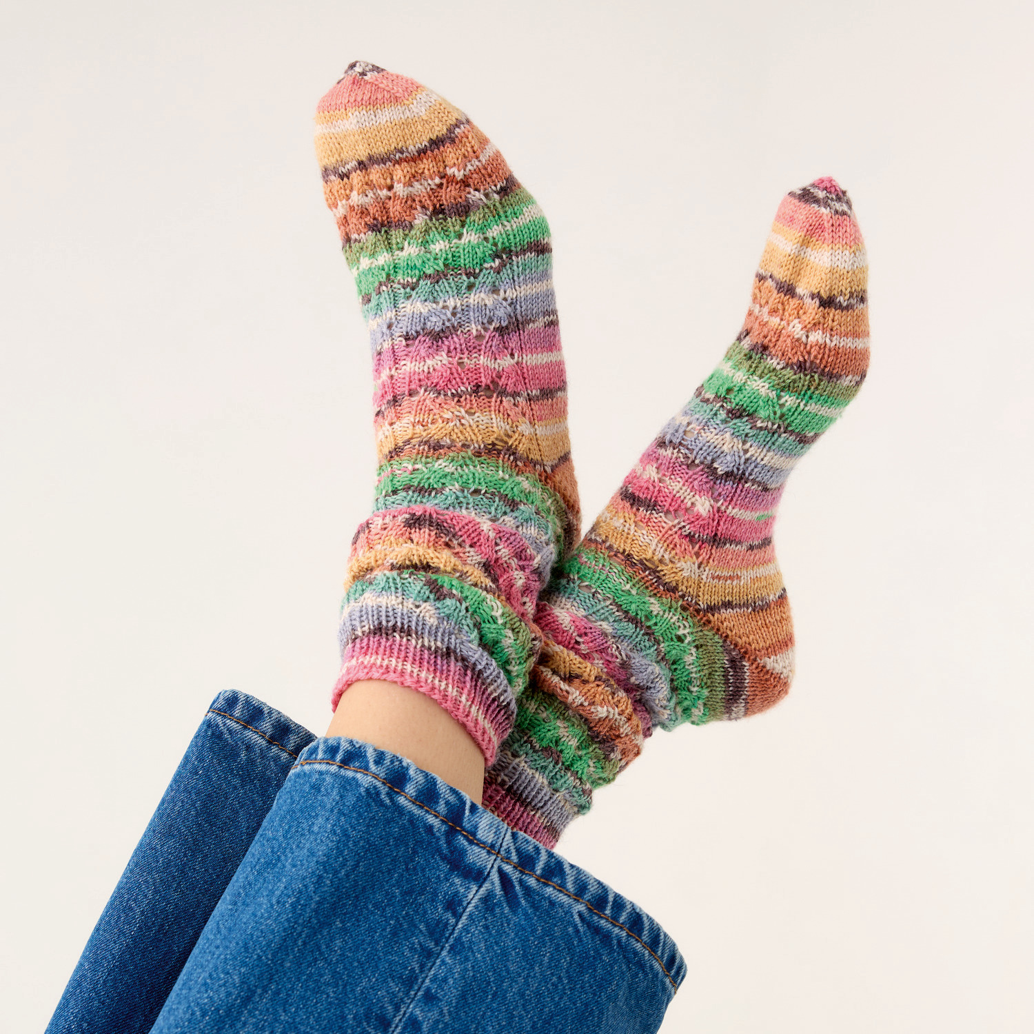 Strickset Socken Modell 02: Bunte, gestreifte Socken an Füßen in blauen Jeans, gestrickt aus Die Neue Masche Nr. 9.