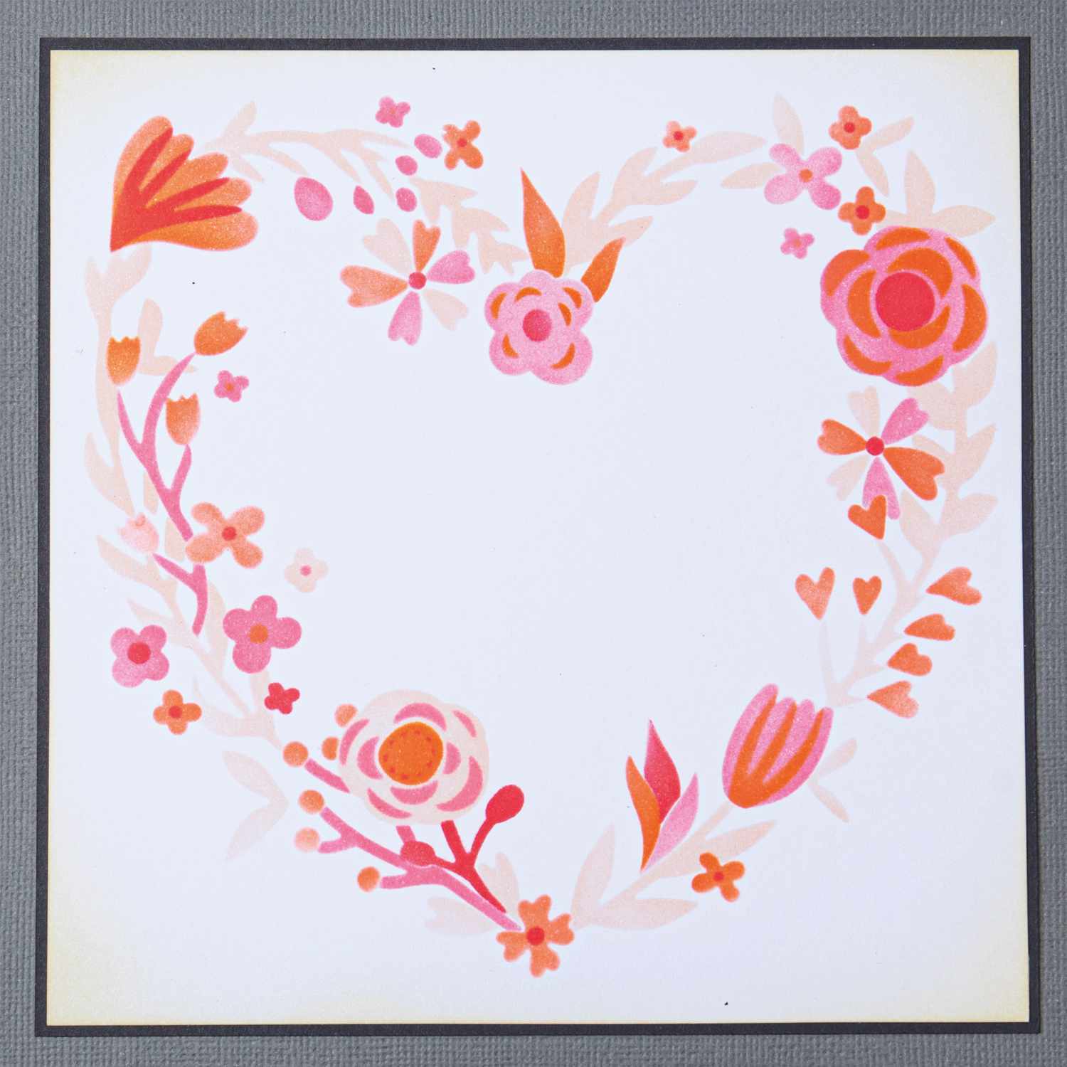 Layered Stencils Heart Wreath by Olivia: Herzkranz aus rosa und orangefarbenen Blumen, ideal für kreative Projekte. Marke: Sizzix.