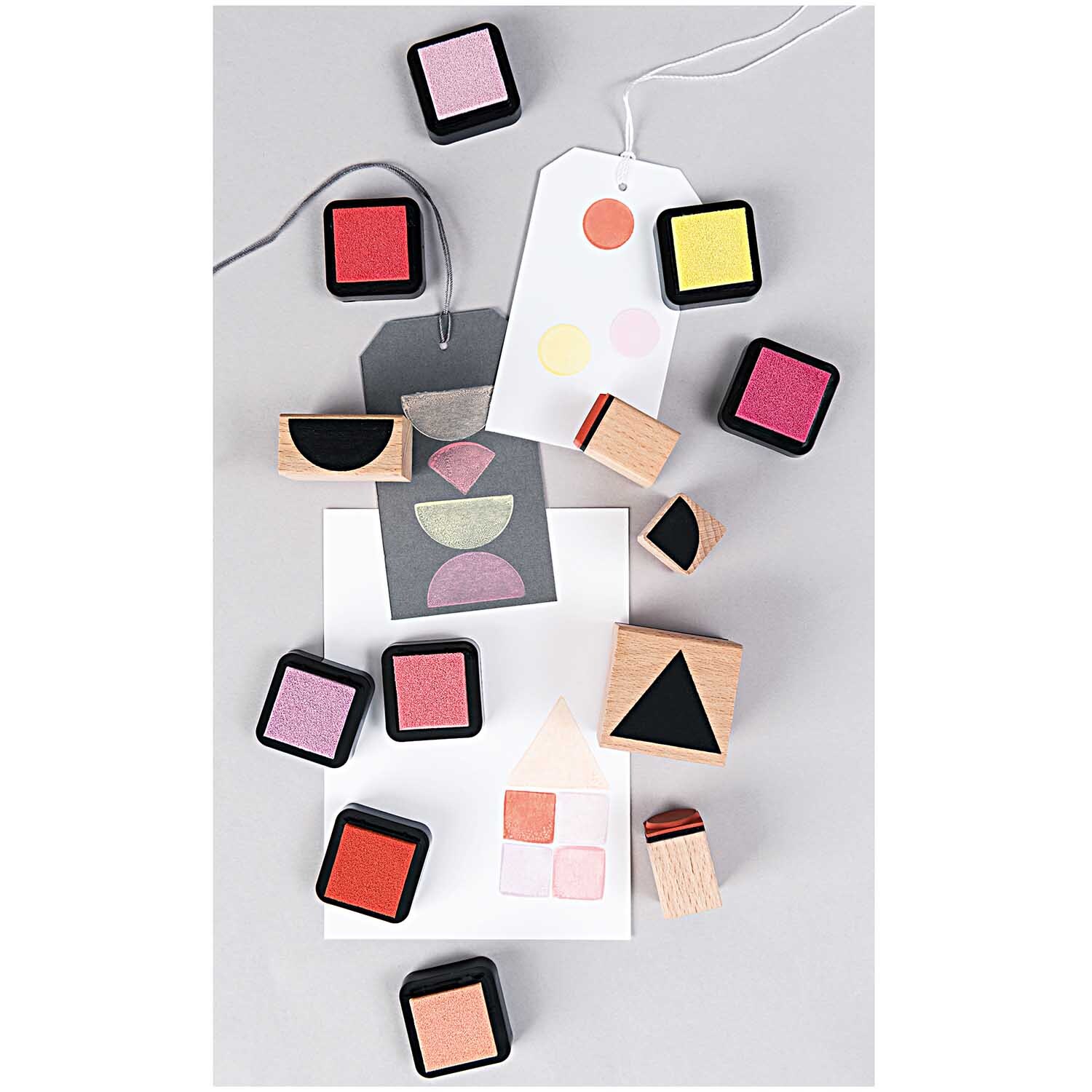 Paper Poetry Stempelset geometrische Symbole eckig, 7-teilig von Rico Design, zeigt bunte Stempelkissen und geometrische Holzstempel auf grauem Hintergrund.