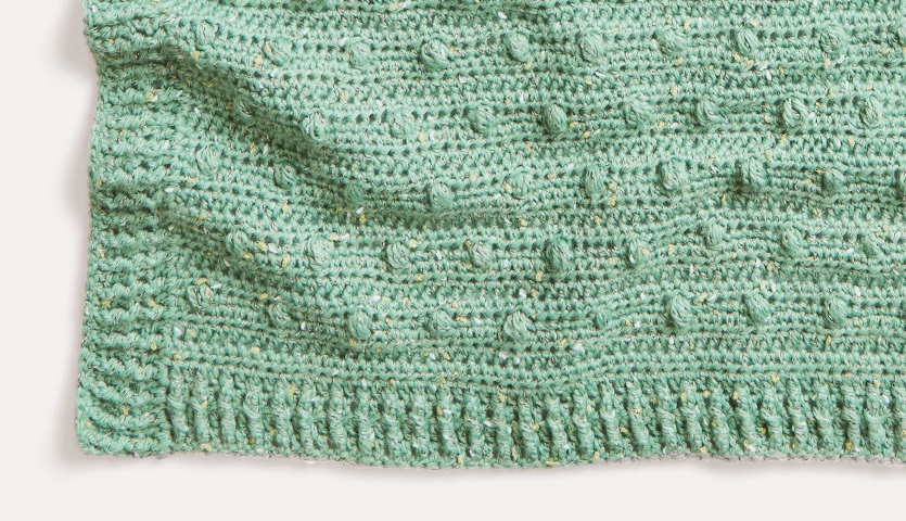 Häkelanleitung Babydecke aus Baby Dream Tweed dk: Detailansicht einer grünen, strukturierten Decke mit feinem Muster.