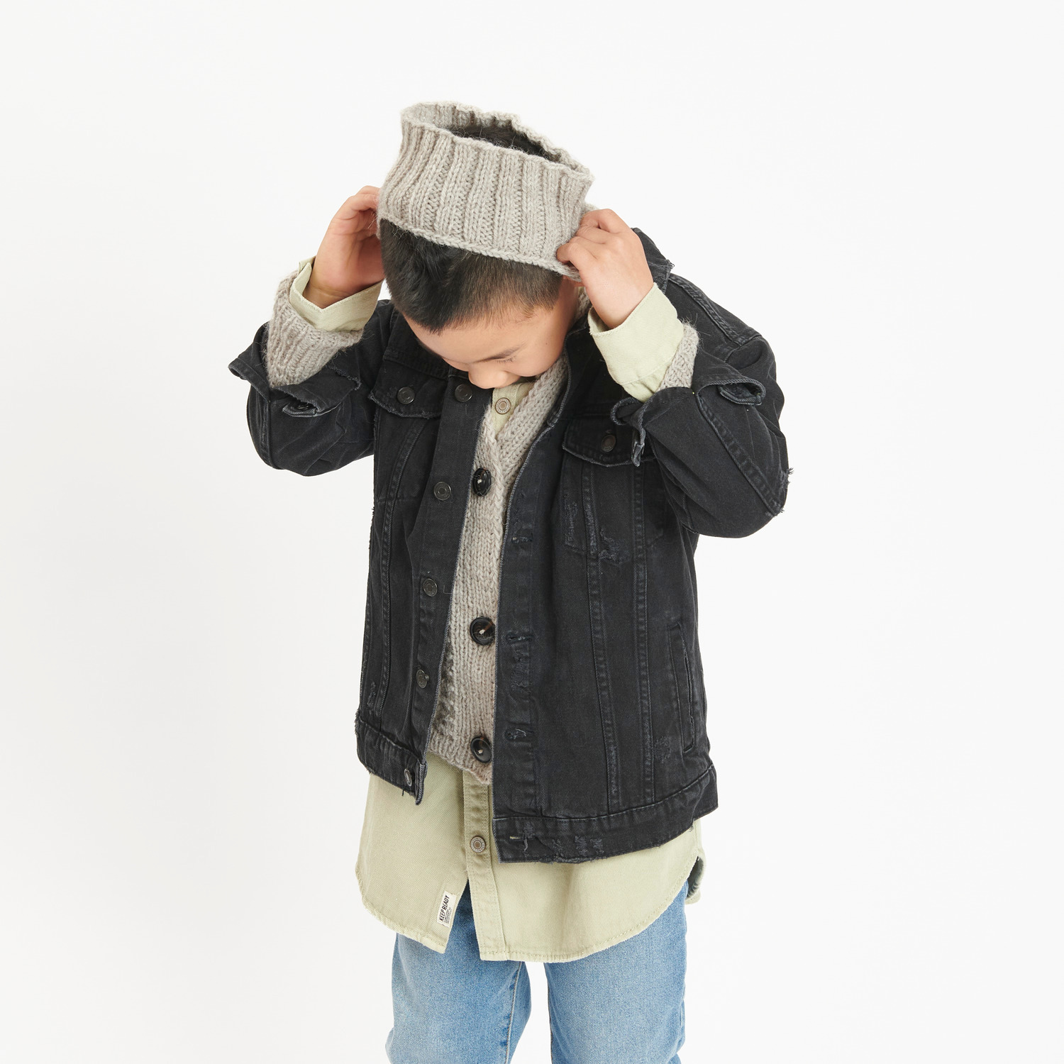Rico Kids 13: Kind in schwarzer Jacke und beiger Mütze aus weicher Alpaka-Wolle von Rico Design.