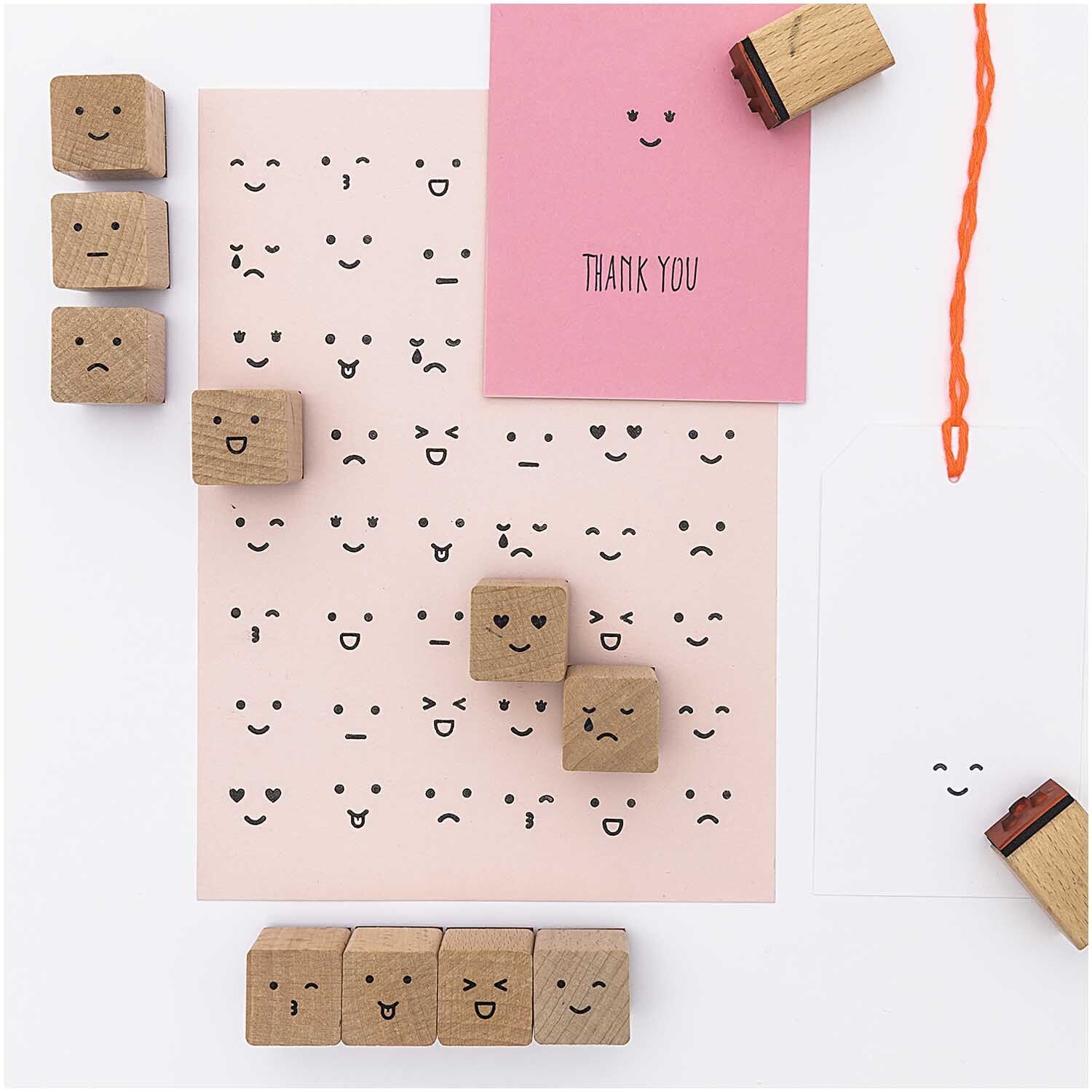 Paper Poetry Stempelset Smile, 13-teilig, zeigt verschiedene Gesichtsausdrücke auf rosa Papier.