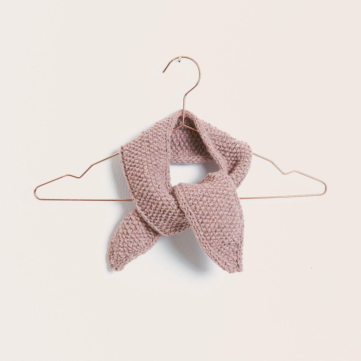 Strickset Tuch Modell 05: Ein rosa gestricktes Tuch auf einem Kleiderbügel, von Rico Design.