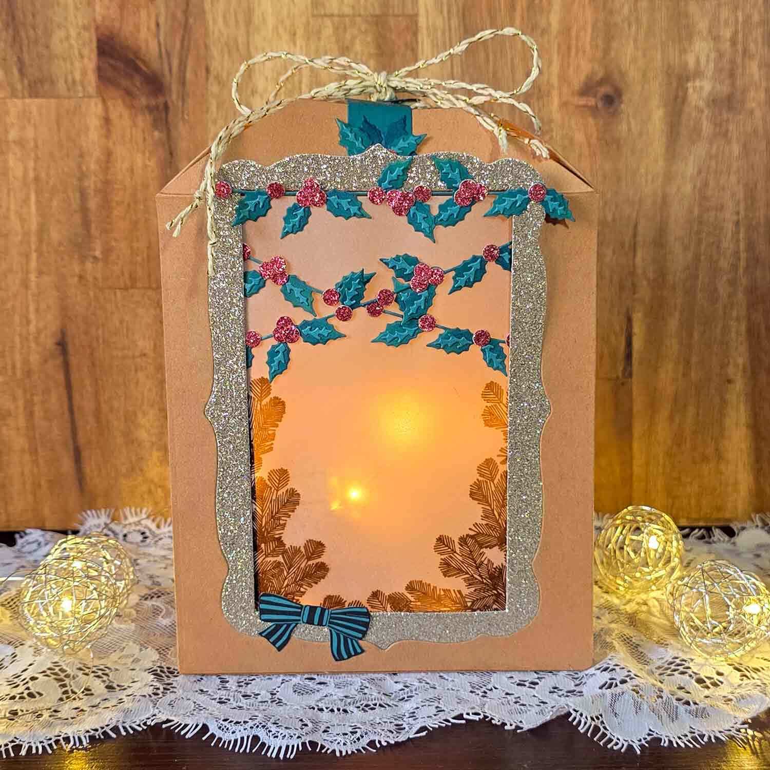 Inspiration Weihnachtslaterne basteln mit Sizzix: Handgemachte Laterne mit goldenen Akzenten und festlichen Verzierungen auf Holzuntergrund.