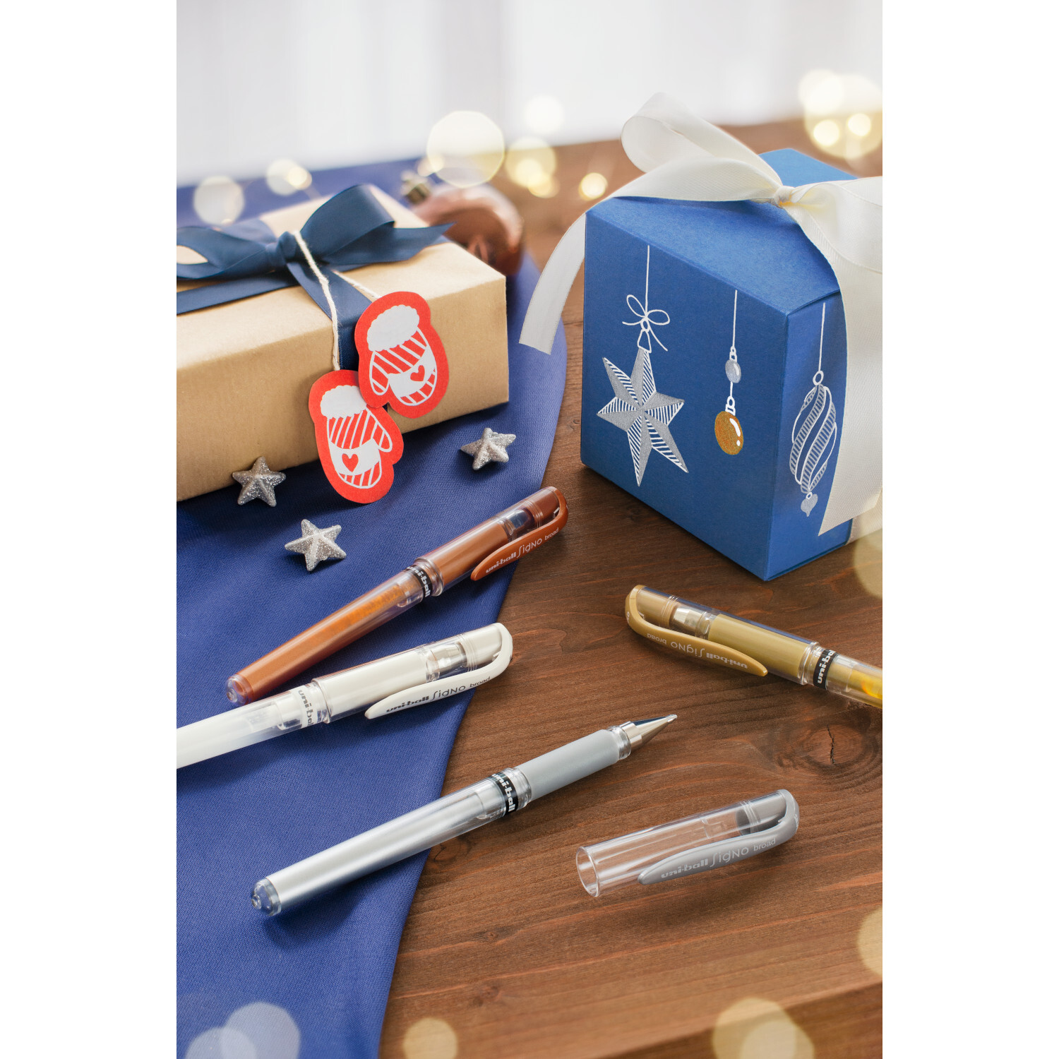 Uni-Ball Signo Broad UM-153 Gelroller 1mm in verschiedenen Farben auf einem Holztisch mit Geschenken.