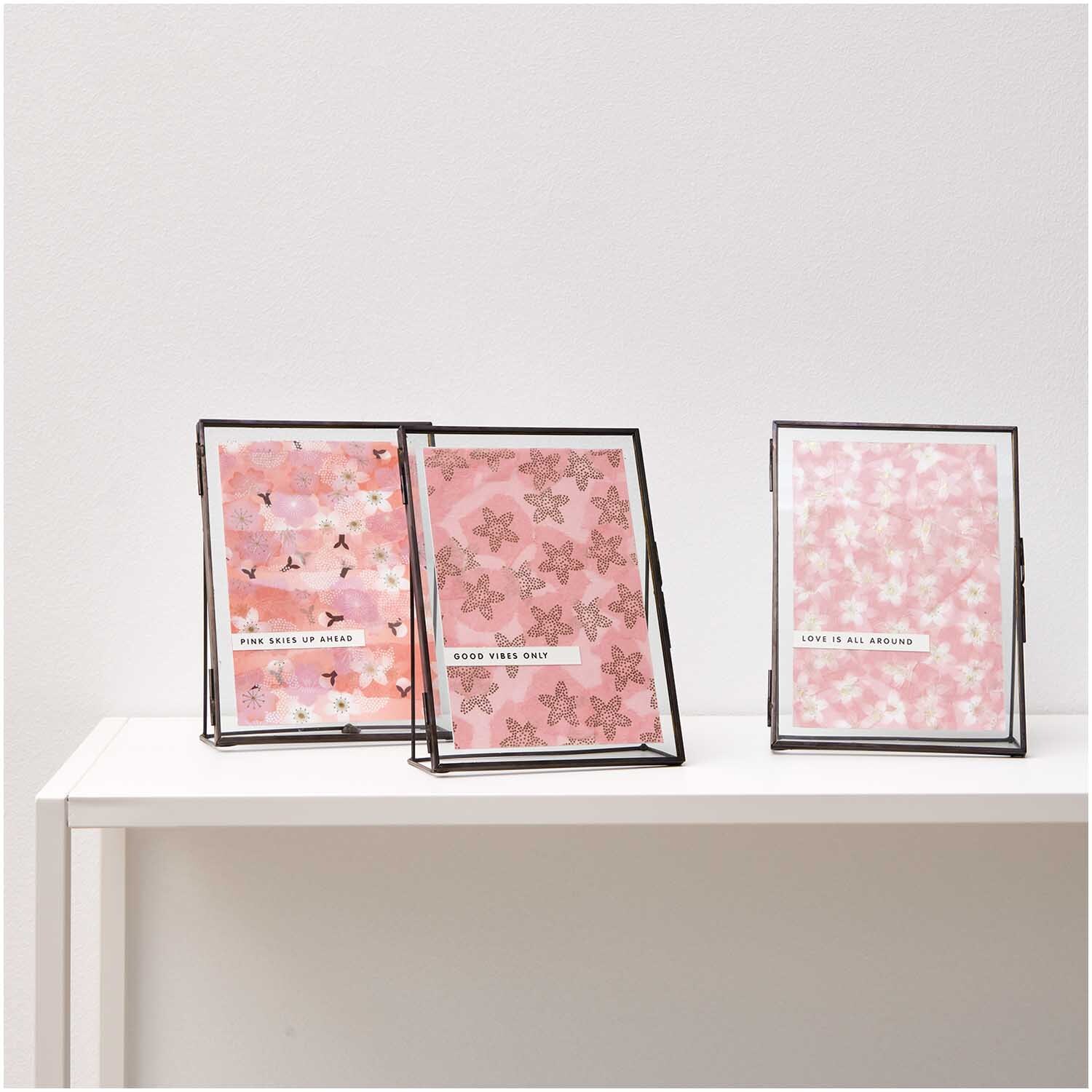 Paper Poetry Paper Patch Papier mit goldenen Kirschblüten in Rosa, präsentiert in drei Rahmen auf einem weißen Tisch.