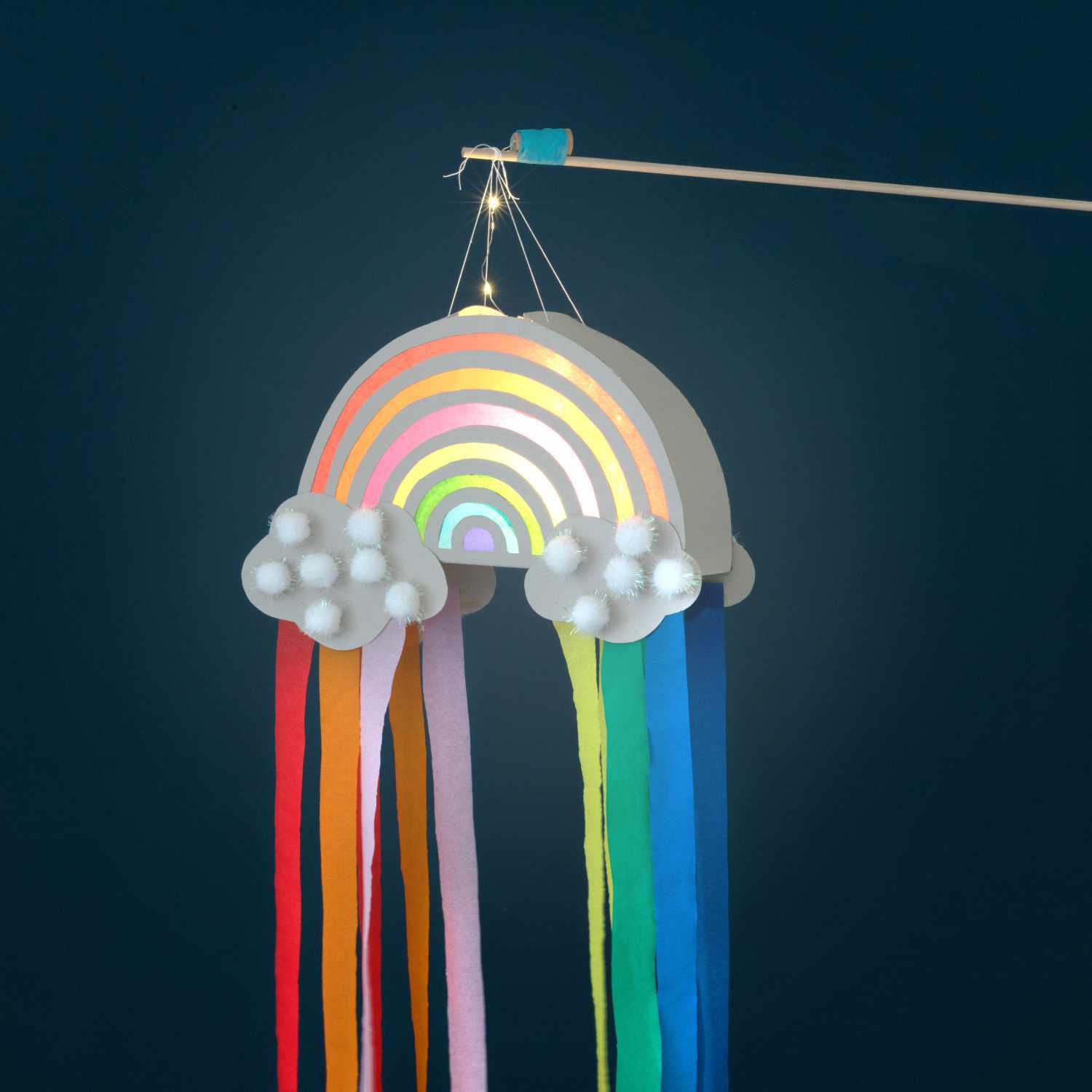 Bastelanleitung Regenbogen-Laterne: Eine bunte Laterne in Regenbogenform mit Wolken und farbigen Bändern.