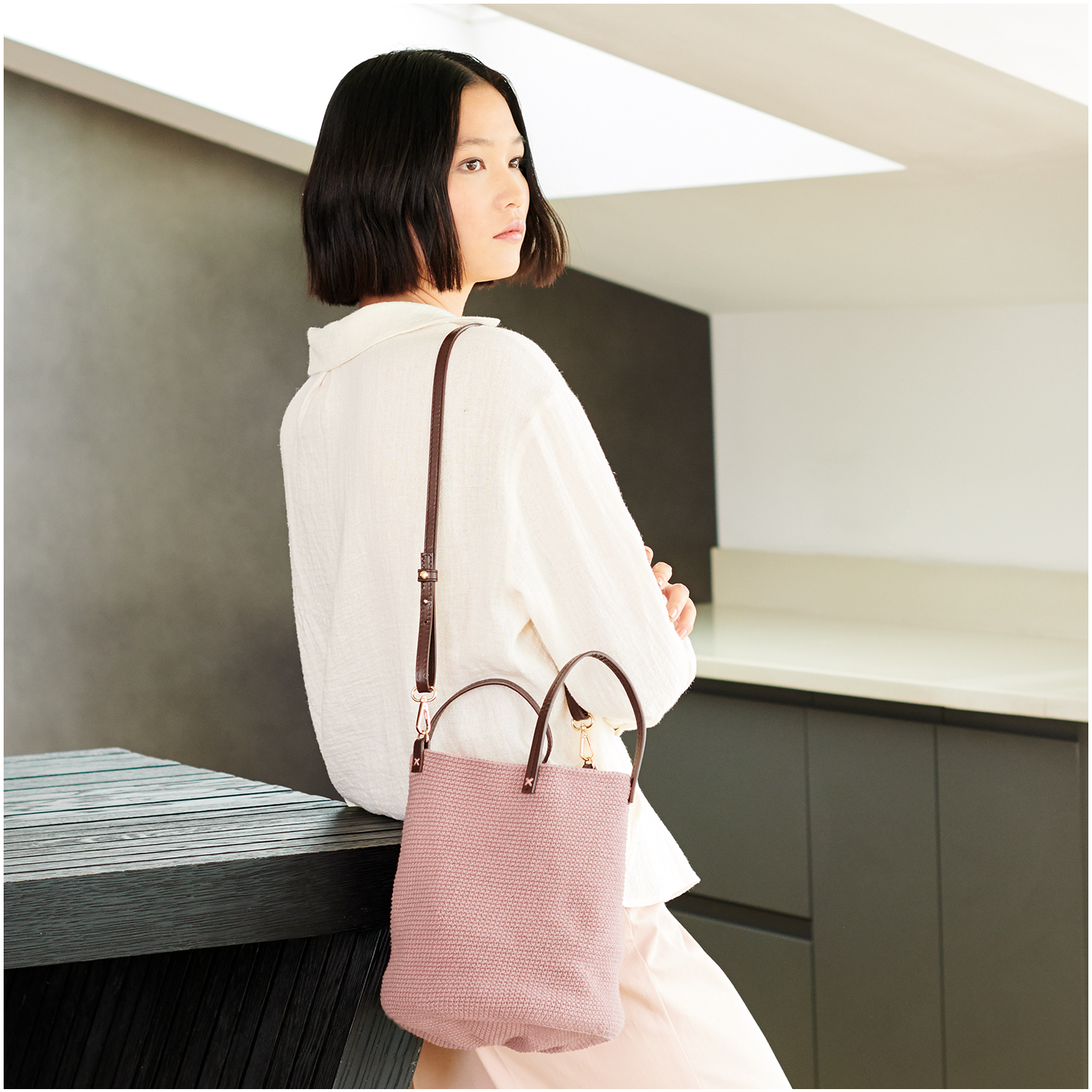 Häkelset Tasche Modell 08a aus Lovewool Nr. 18, rosa, über der Schulter einer Frau in heller Kleidung.