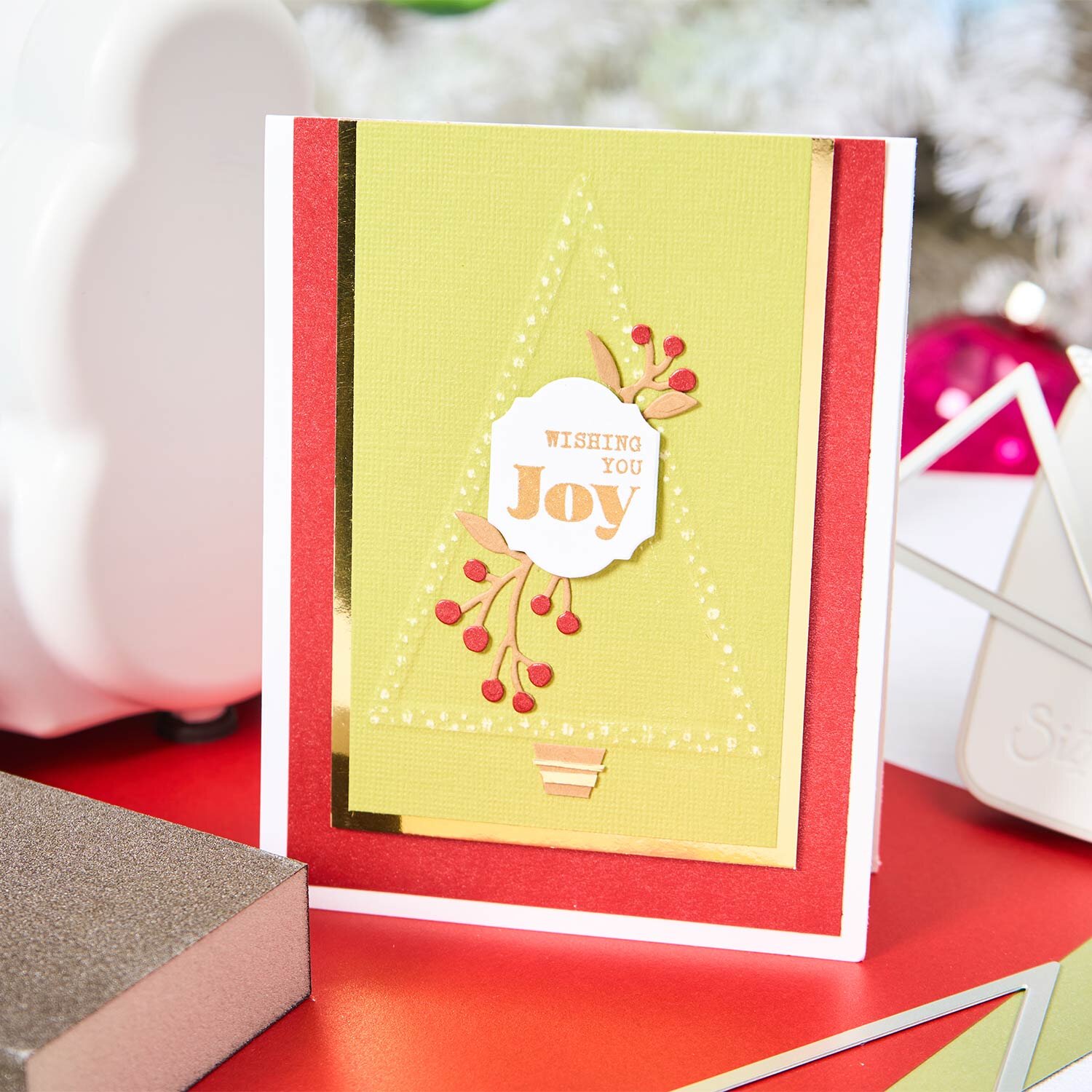 Sizzix Framelits Die Set Perfect Triangles: Weihnachtskarte mit gelbem Dreieck und roten Beeren auf rotem Tisch.