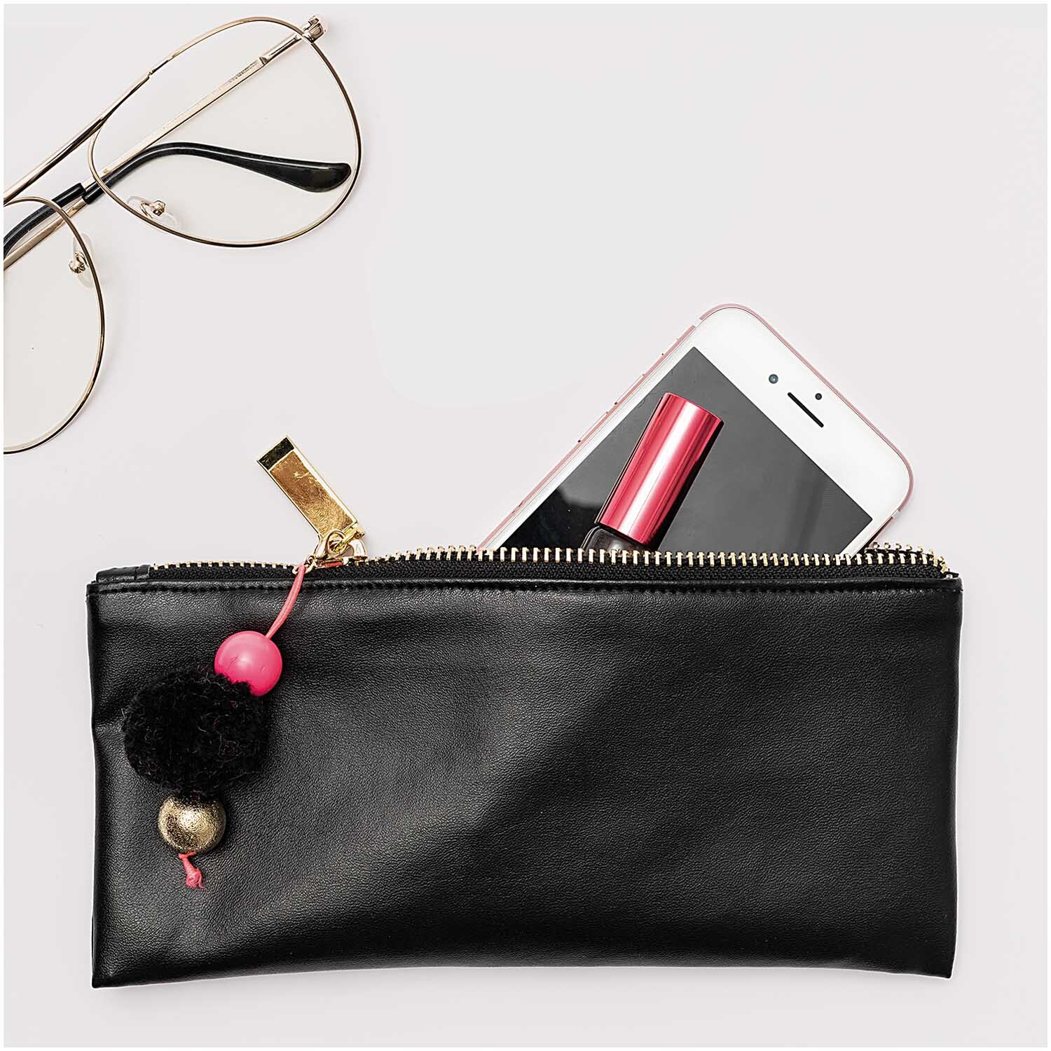 Kunstleder matt 45x100cm: Schwarzes Etui von Rico Design mit Reißverschluss, gefüllt mit Smartphone und Lippenstift.