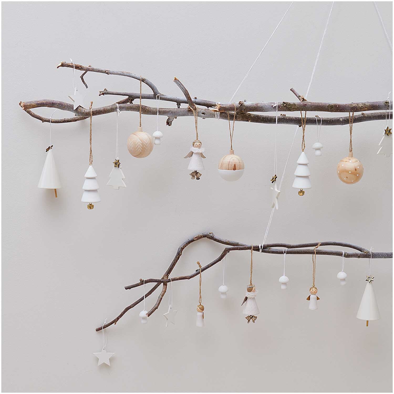 Baumschmuck Holzkugel natur-weiß Ø6cm von Rico Design an Zweigen mit weiteren Dekorationen.