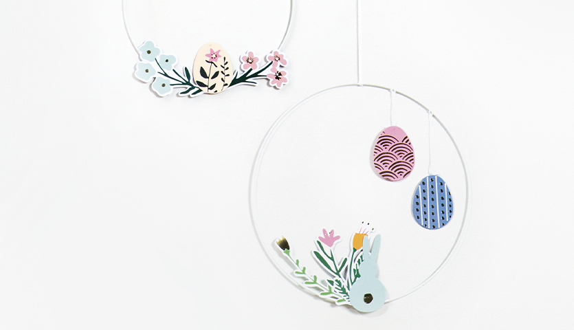 Bastelanleitung Wanddeko für Ostern: Zwei dekorative Ringe mit Blumen und bunten Ostereiern.