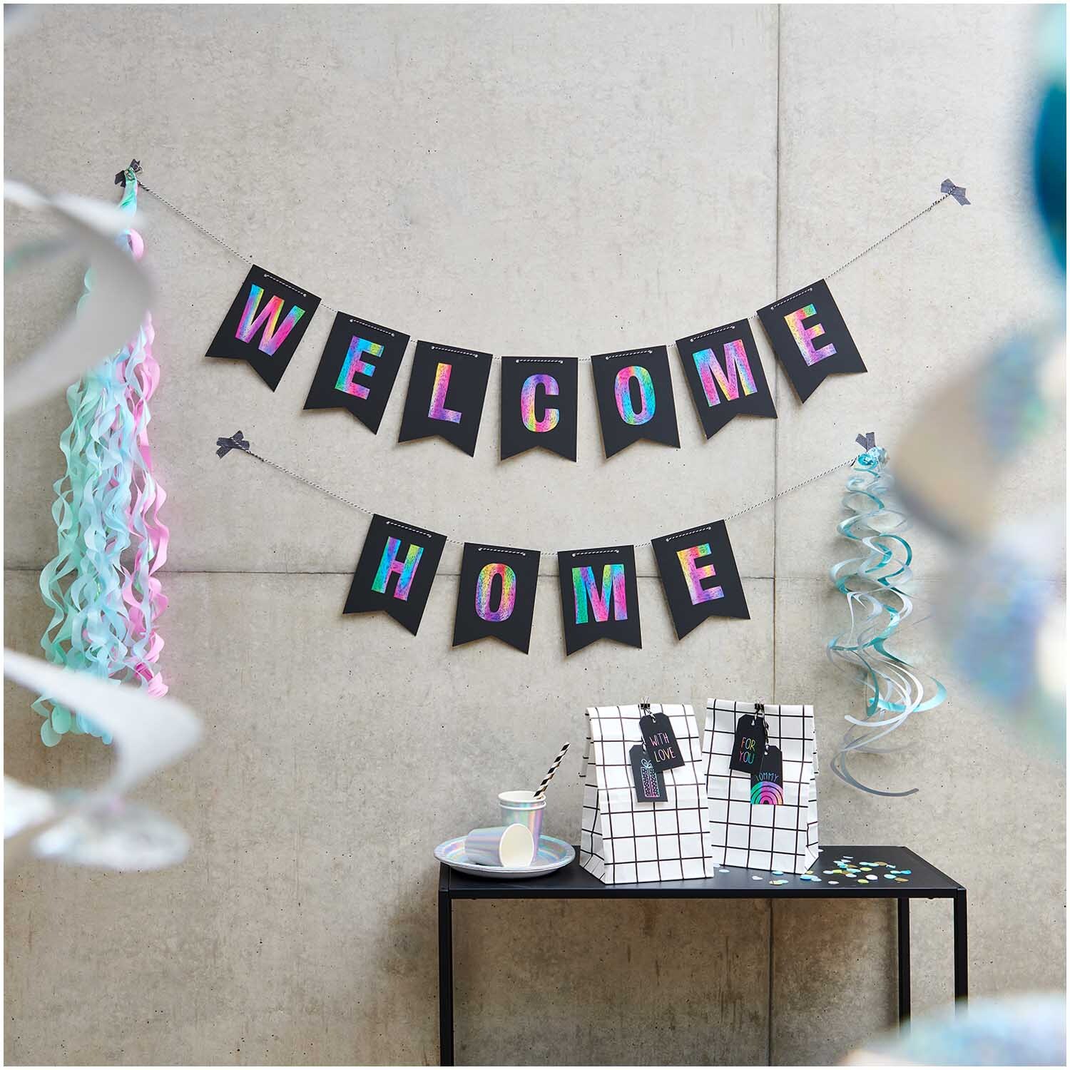 Paper Poetry Holzkratzer Set von Rico Design, dekoriert mit bunten Girlanden und einem "Welcome Home"-Banner.