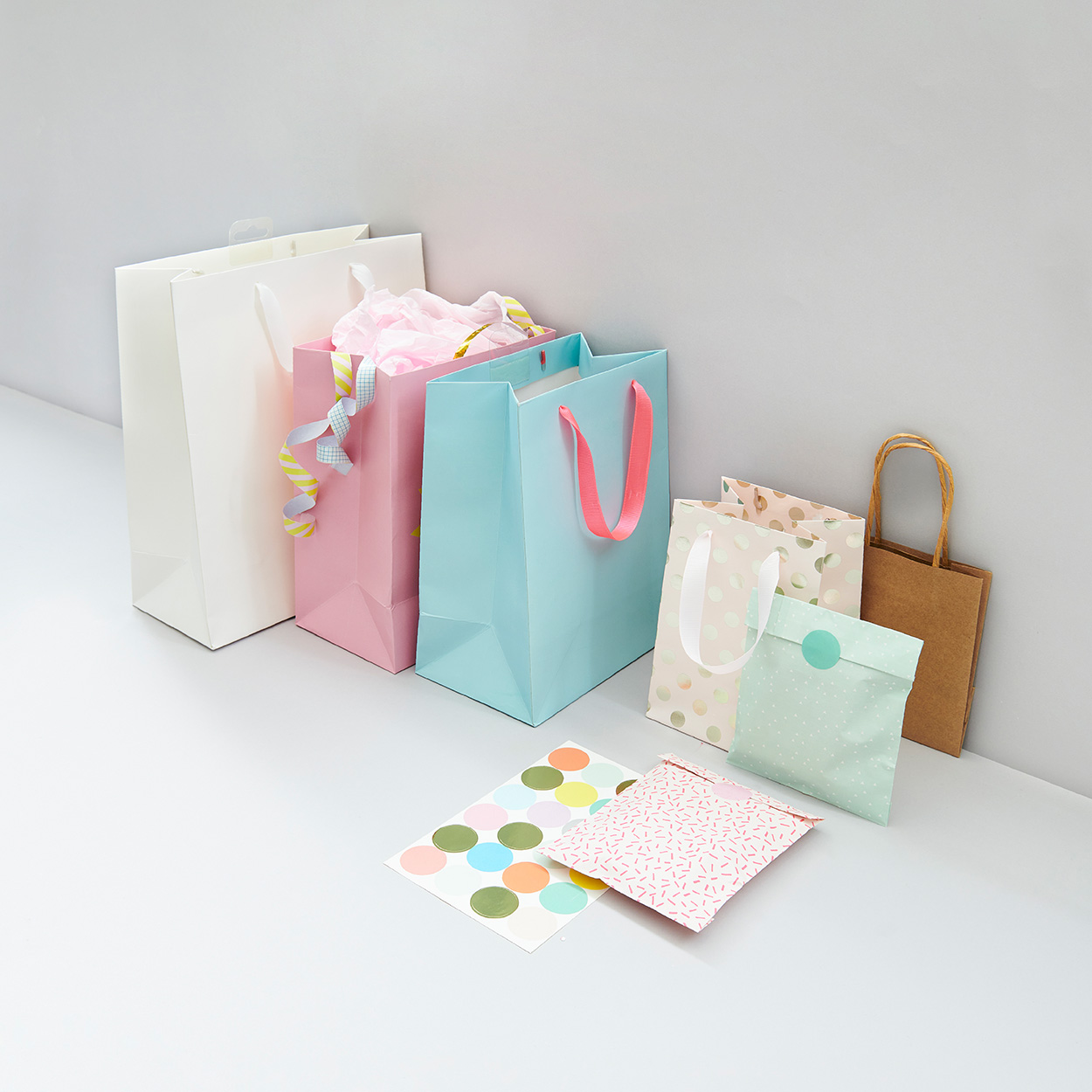 Papier- und Geschenktüten in verschiedenen Farben und Größen. Fotosetting graue Ecke.