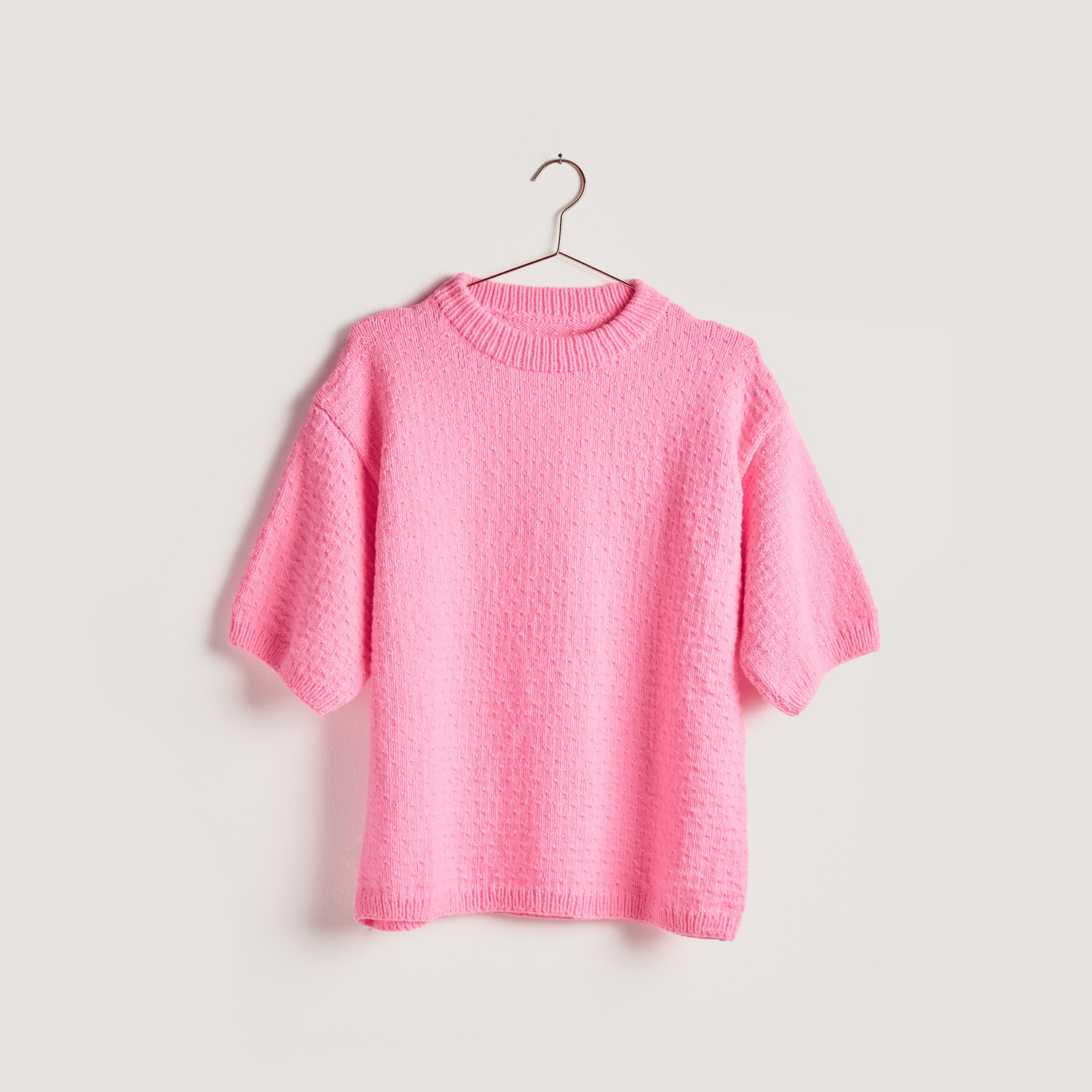 Strickset Shirt Modell 13b aus Vegan Cashmere in leuchtendem Pink von Rico Design, auf einem Bügel präsentiert.