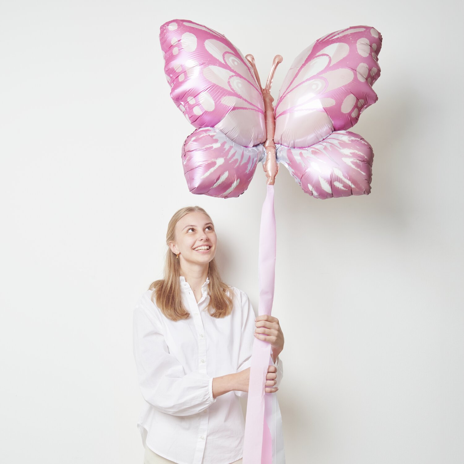 Folienballon Schmetterling Pink/Orange: Eine Person hält einen großen, pink-orangefarbenen Schmetterlingsballon von Rico Design.