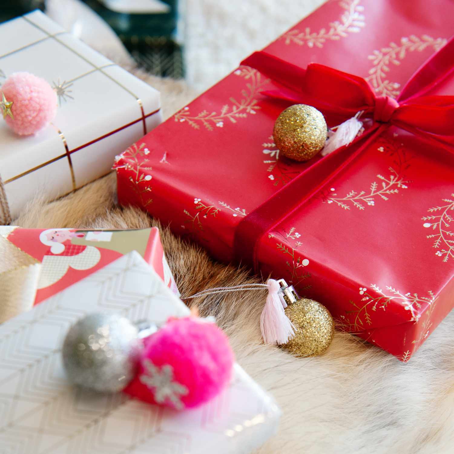 Pompon- und Kugel-Anhänger neon-pastell 6 Stück von Rico Design dekorieren festliche Geschenke in verschiedenen Farben auf einem Fell.