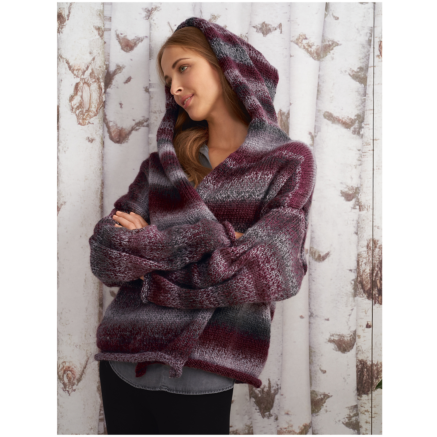 Creative Ito Iro Chunky: Frau in gestricktem Kapuzenpullover in Bordeaux Mix vor Birkenwald-Hintergrund.