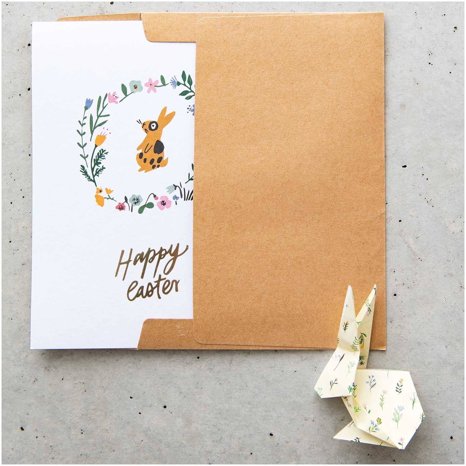 Paper Poetry Postkartenblock Bunny Hop 15 Stück zeigt eine Osterkarte mit Hase und Blumenkranz.