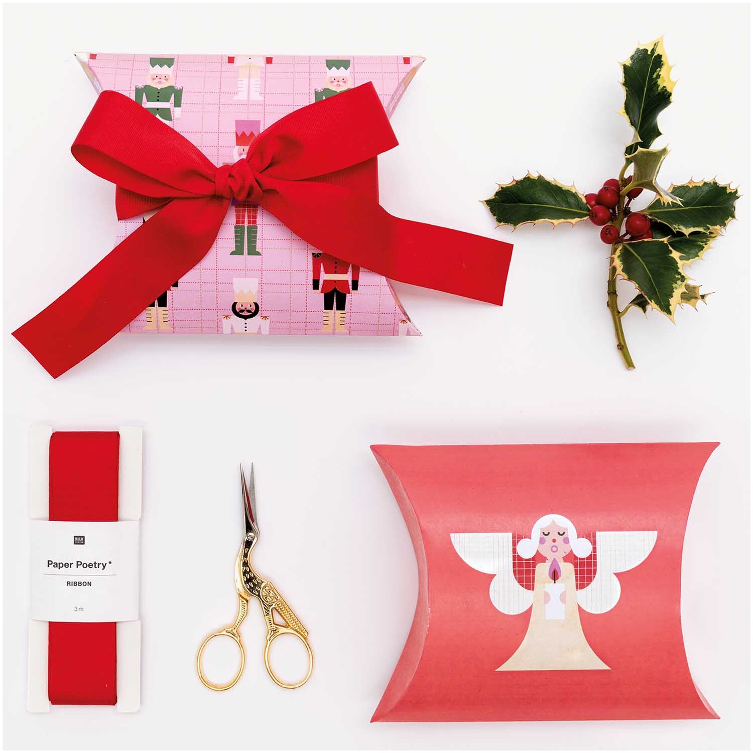 Paper Poetry Geschenkschachtel Weihnachtsfiguren 4 Stück, dekoriert mit rotem Band, Schere und Stechpalme auf weißem Hintergrund.