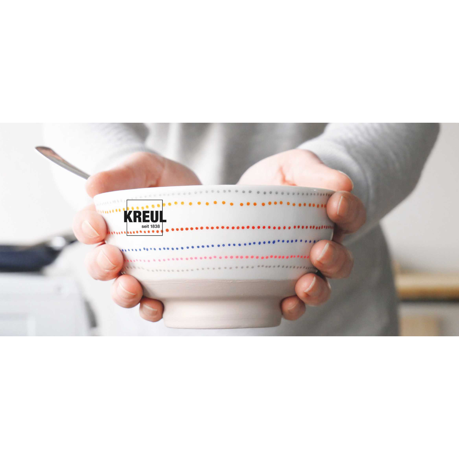 Glass & Porcelain Pen Chalky: Person hält weiße Schale mit bunten Punkten, KREUL-Logo sichtbar.