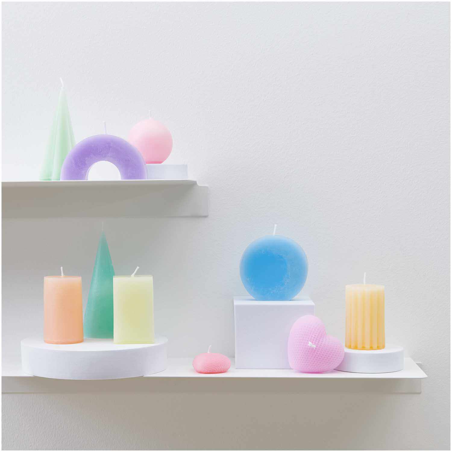 Kerzengießform großes Herz 86x78x43mm von Rico Design. Bunte Kerzen in verschiedenen Formen auf weißen Regalen.
