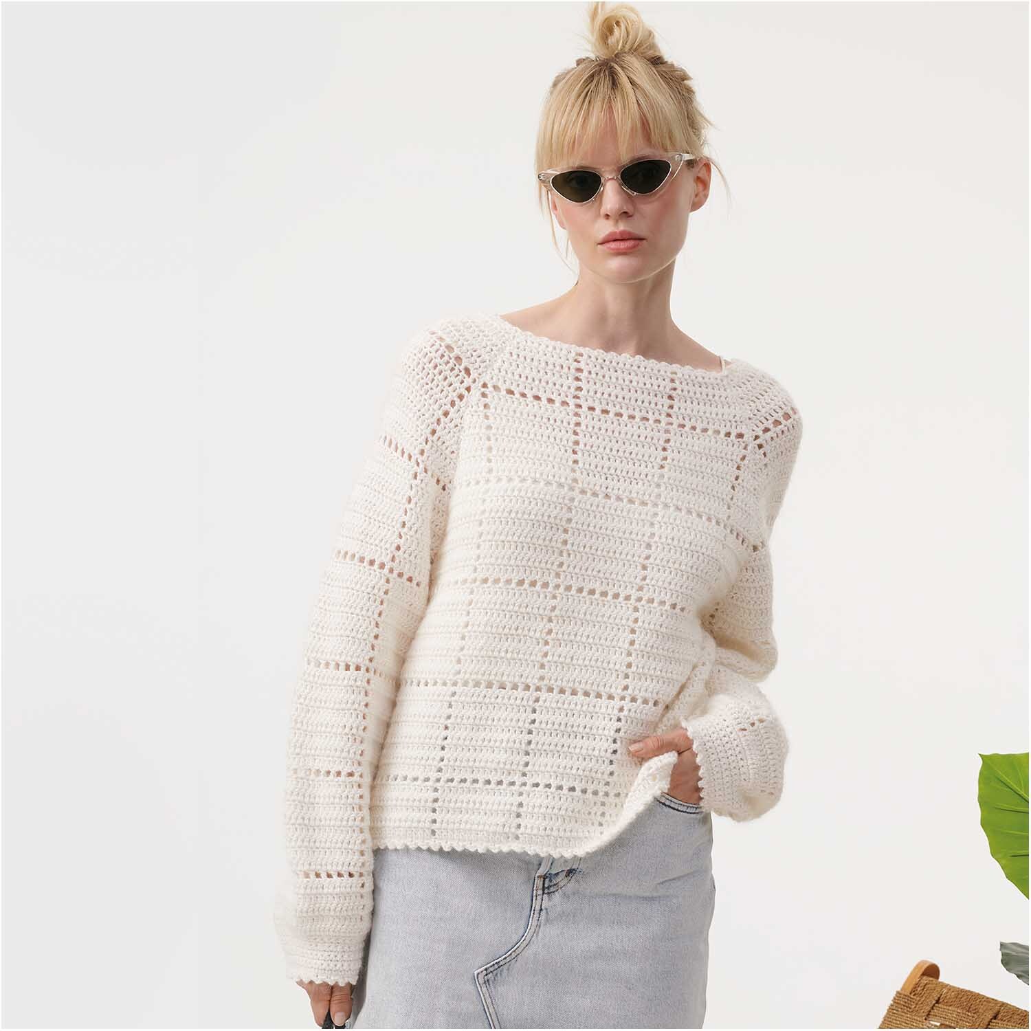 Essentials Super Kid Mohair Loves Silk: Frau in weißem Strickpullover von Rico Design, trägt Sonnenbrille, steht vor hellem Hintergrund.