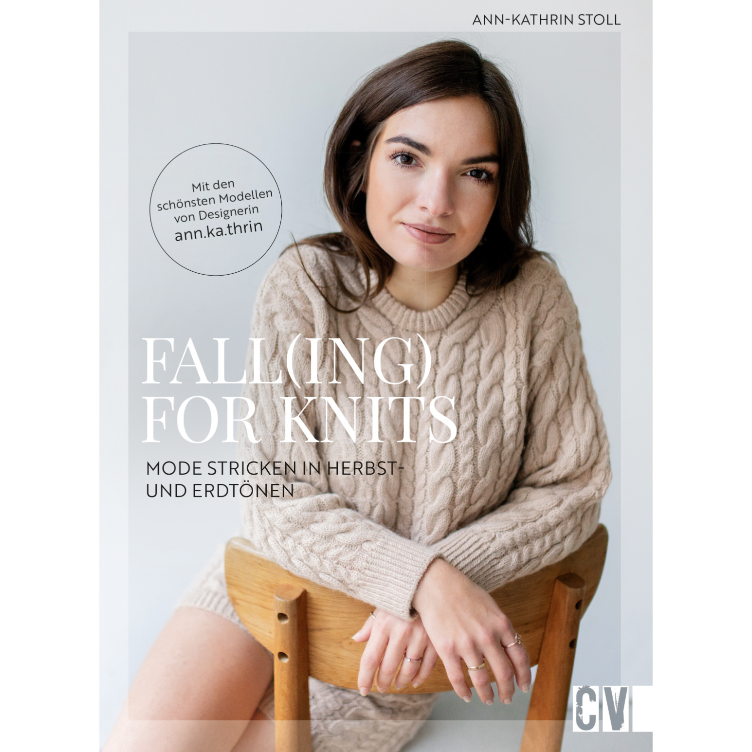 Fall(ing) for Knits - Eine Frau in einem beigen Strickpullover sitzt auf einem Holzstuhl.